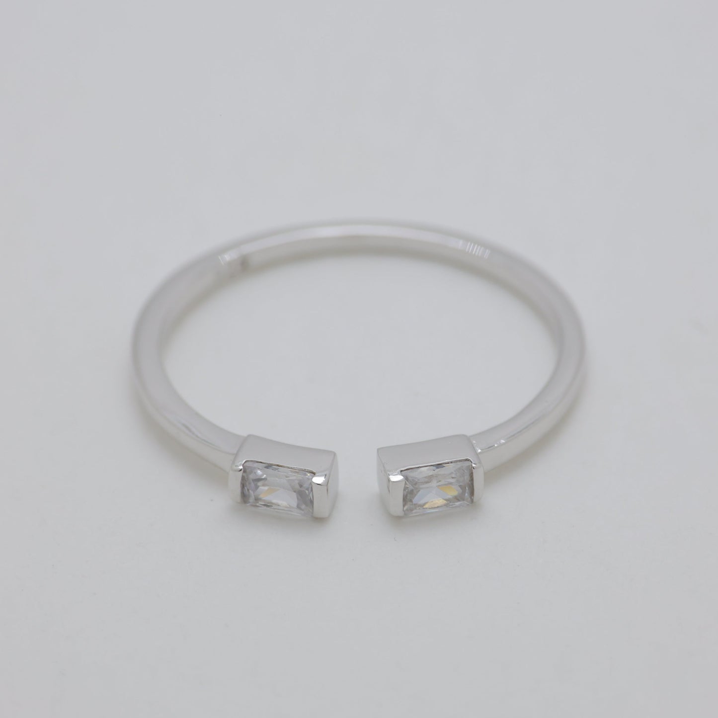 Silver ring with two small stones on a light gray background