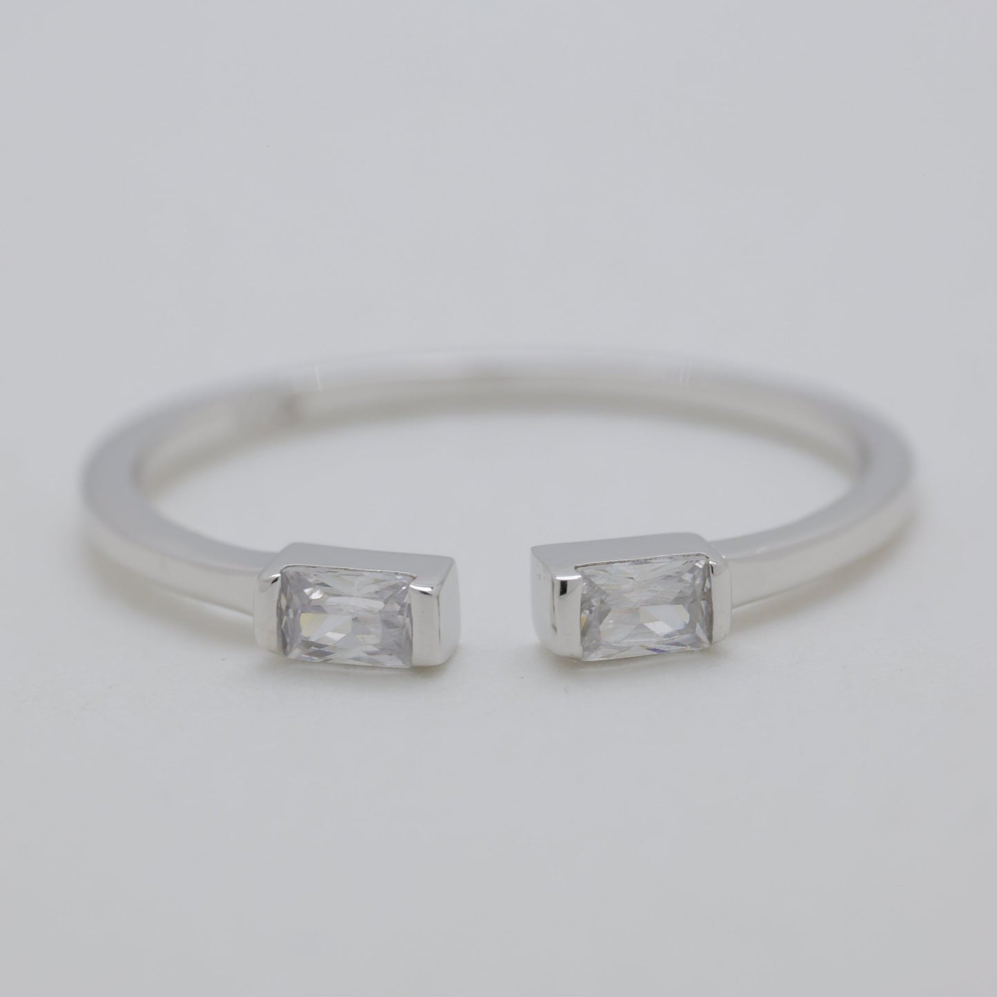 Silver ring with two rectangular gemstones on a light gray background