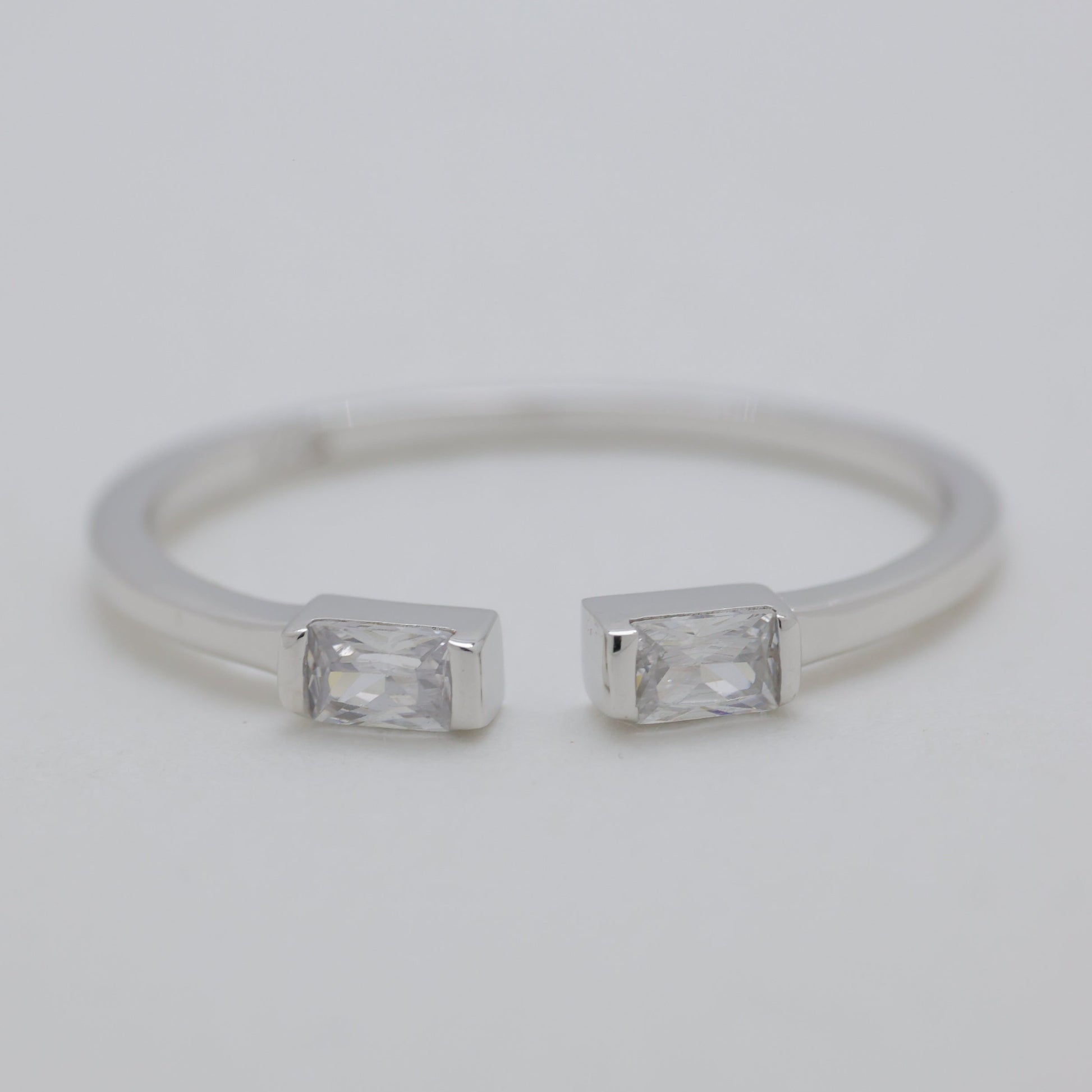 Silver ring with two rectangular gemstones on a light gray background