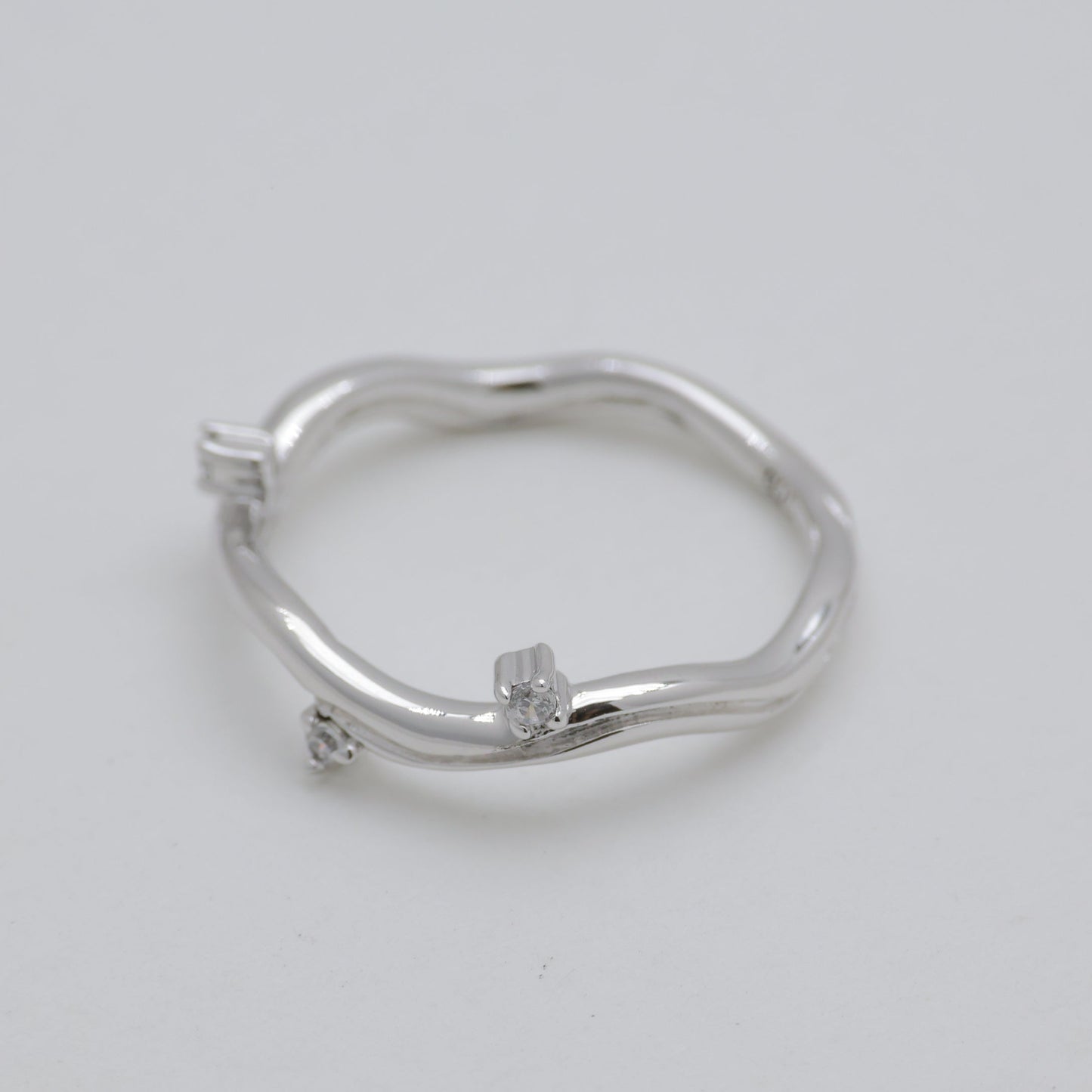 Silver ring with small diamonds on a light gray background