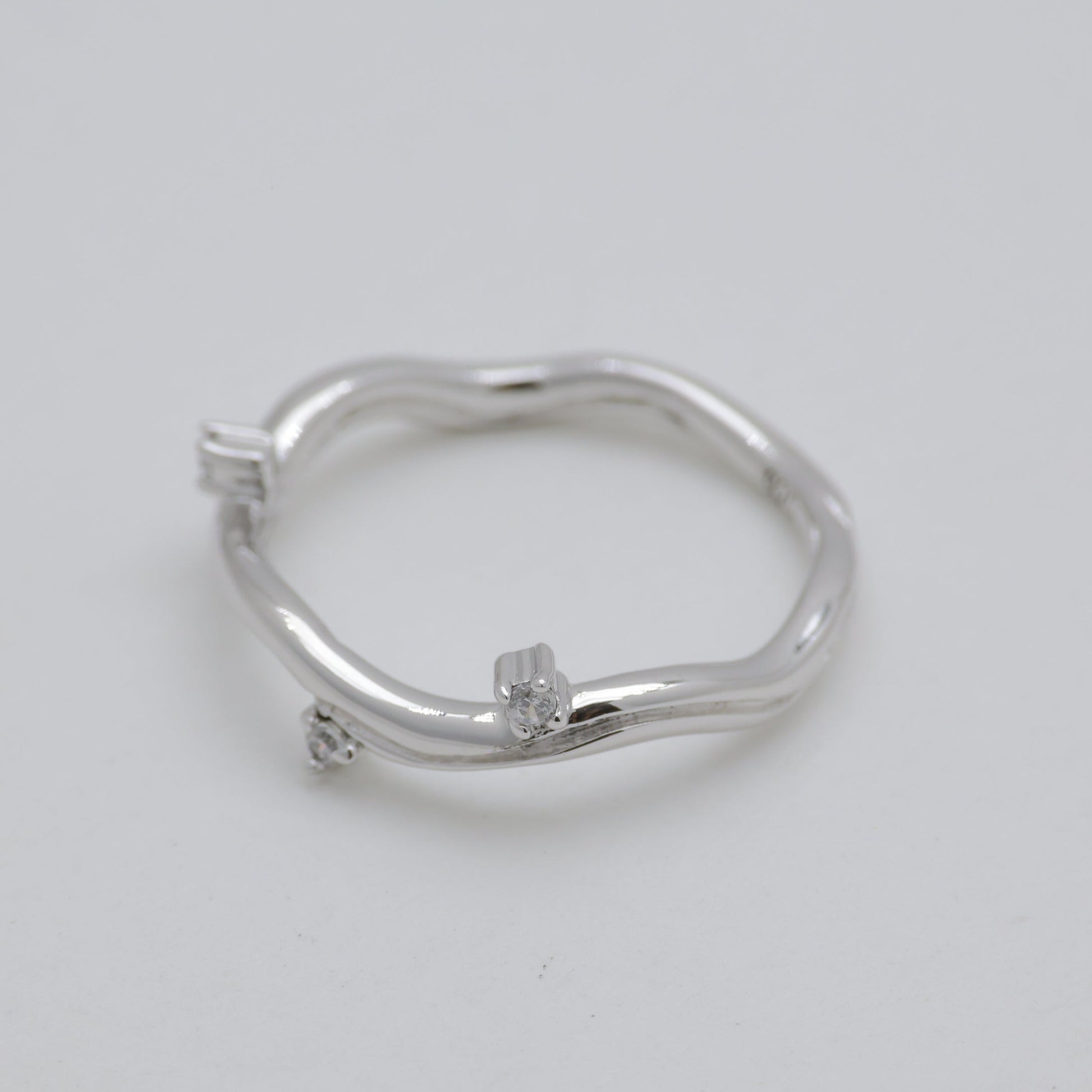 Silver ring with small diamonds on a light gray background