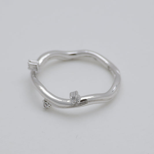 Silver ring with small diamonds on a light gray background