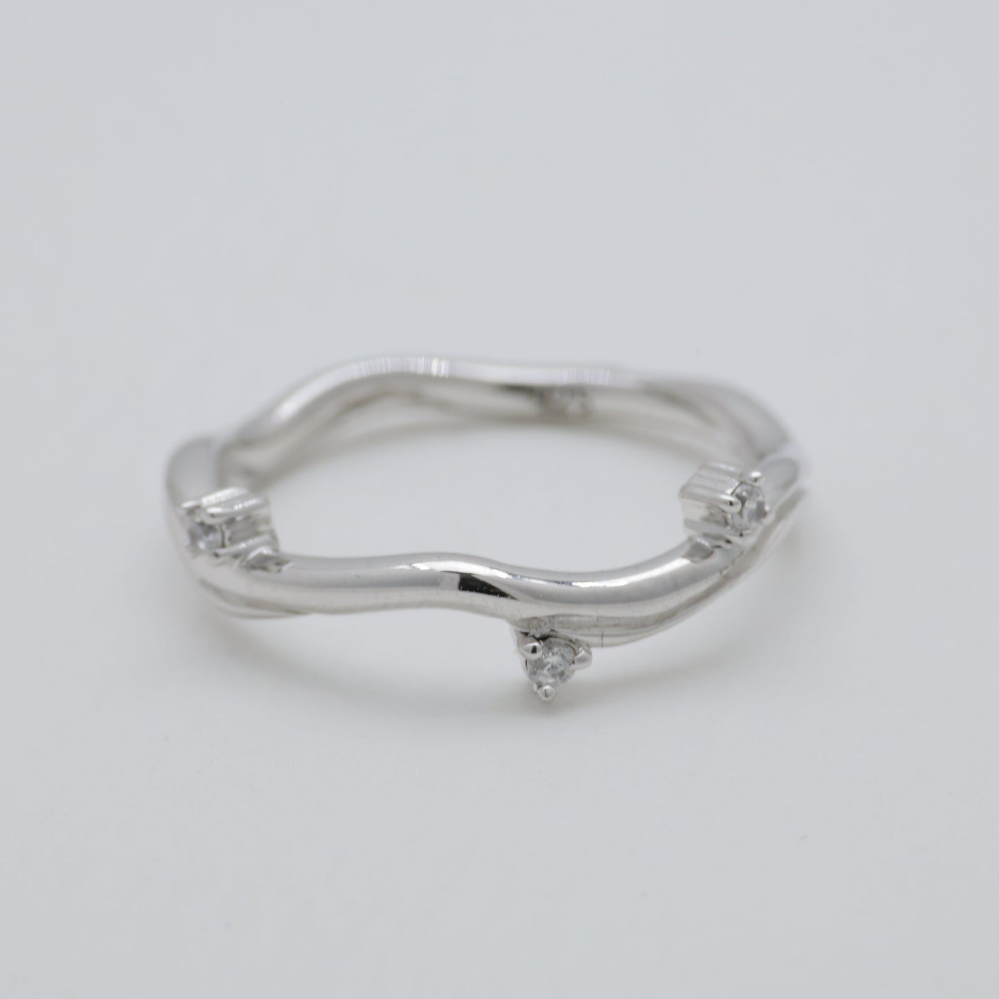 Silver ring with small diamonds on a light gray background