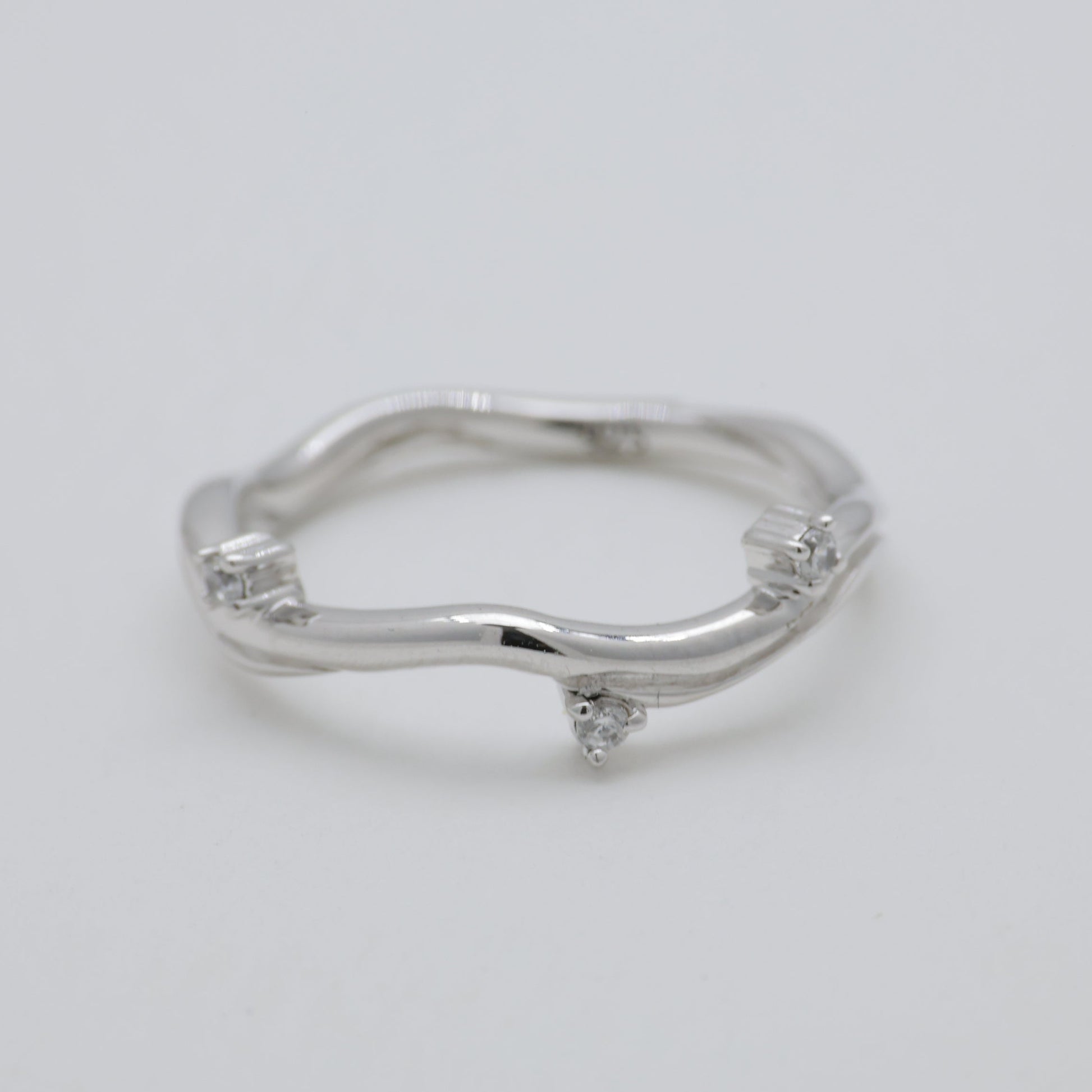 Silver ring with small diamonds on a light gray background