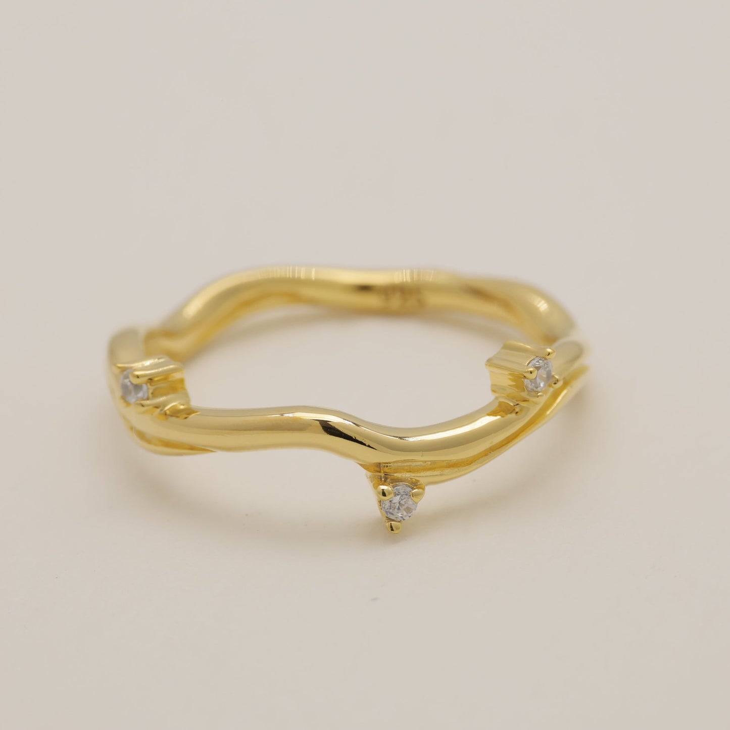 Gold ring with small diamonds on a beige background