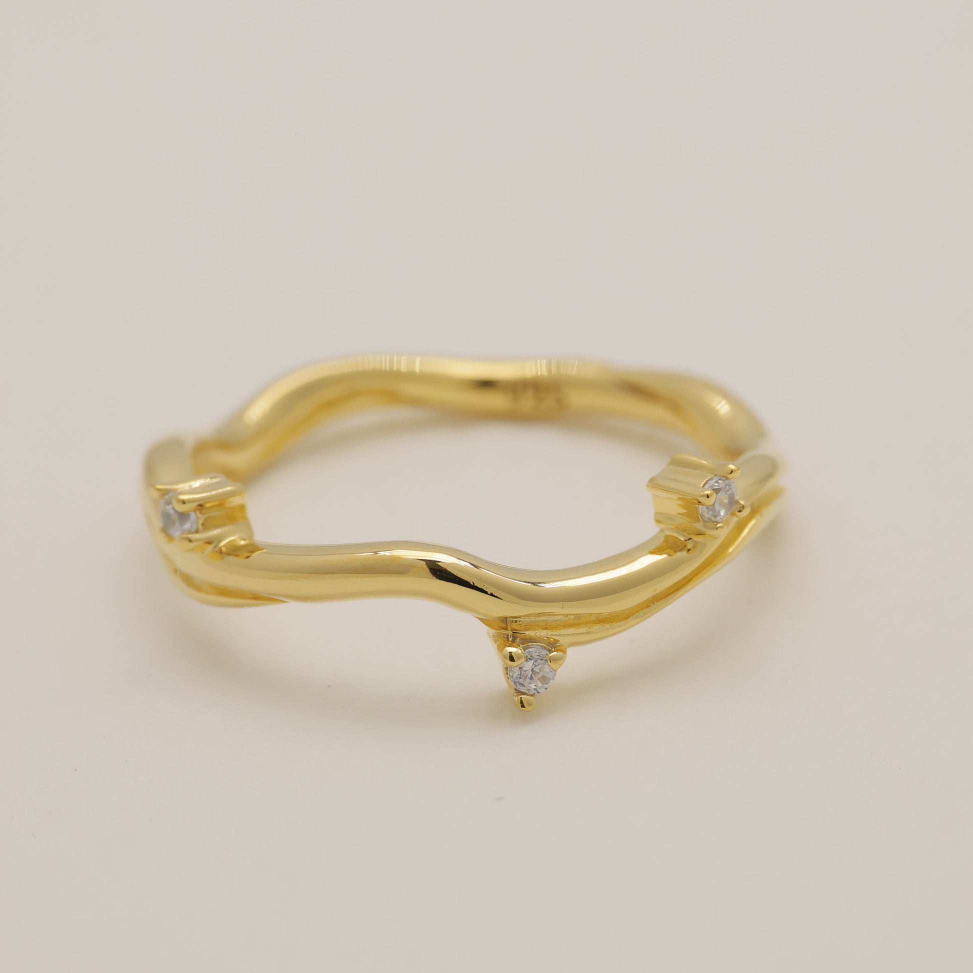 Gold ring with small diamonds on a beige background