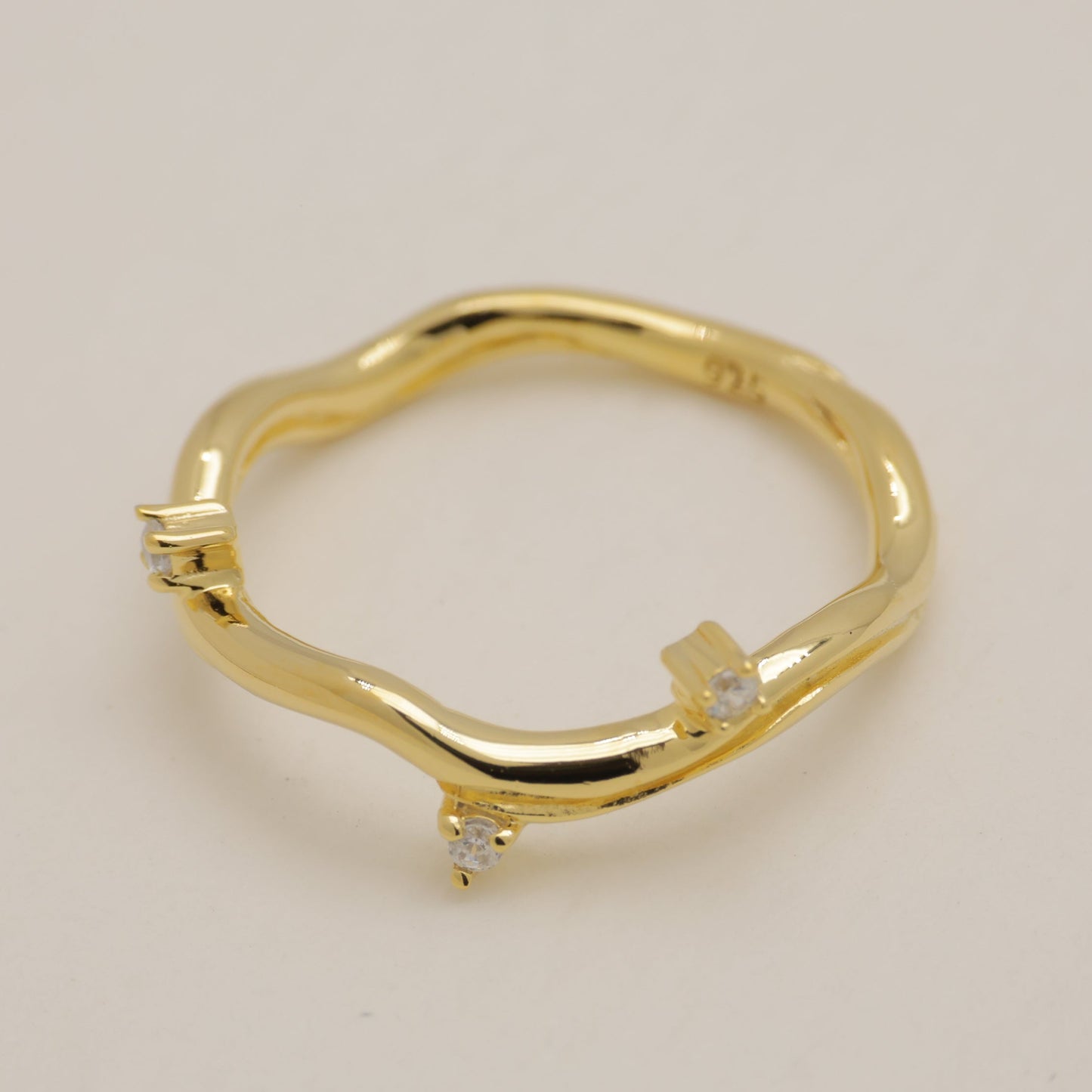 Gold ring with small diamonds on a beige background