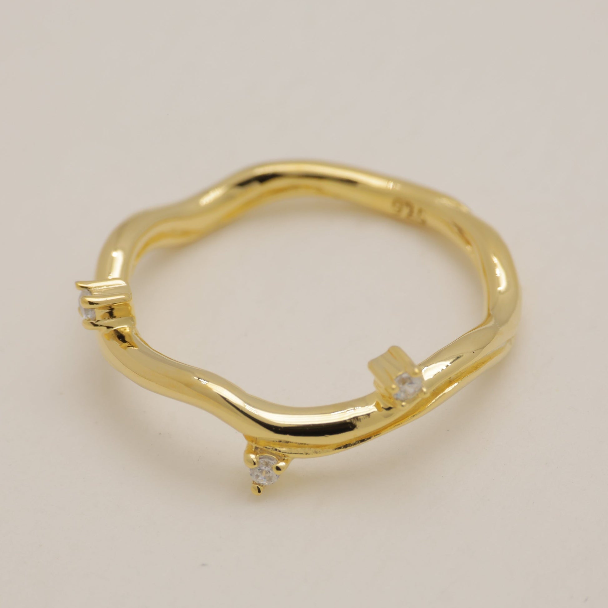 Gold ring with small diamonds on a beige background