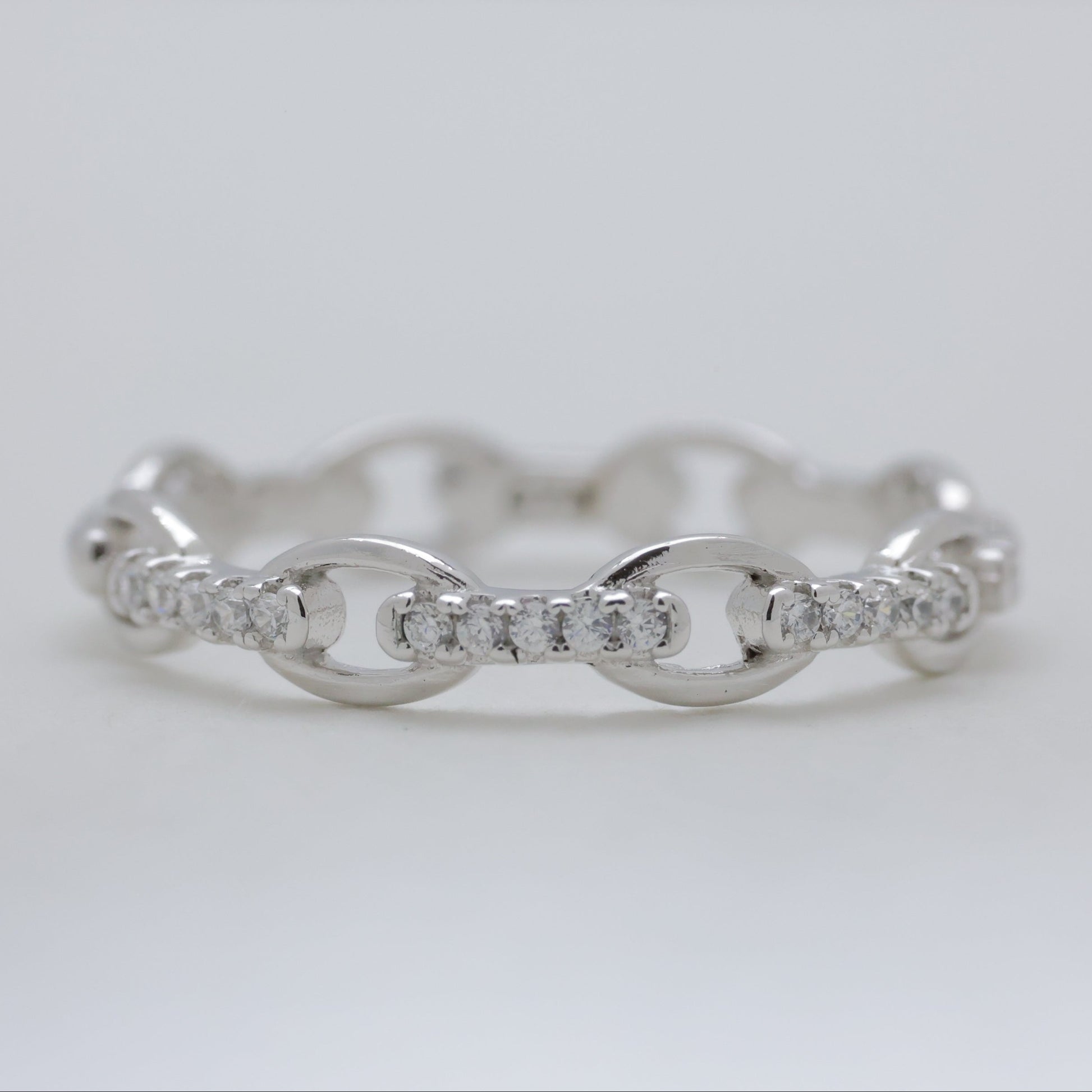 Silver ring with diamond accents on a light gray background