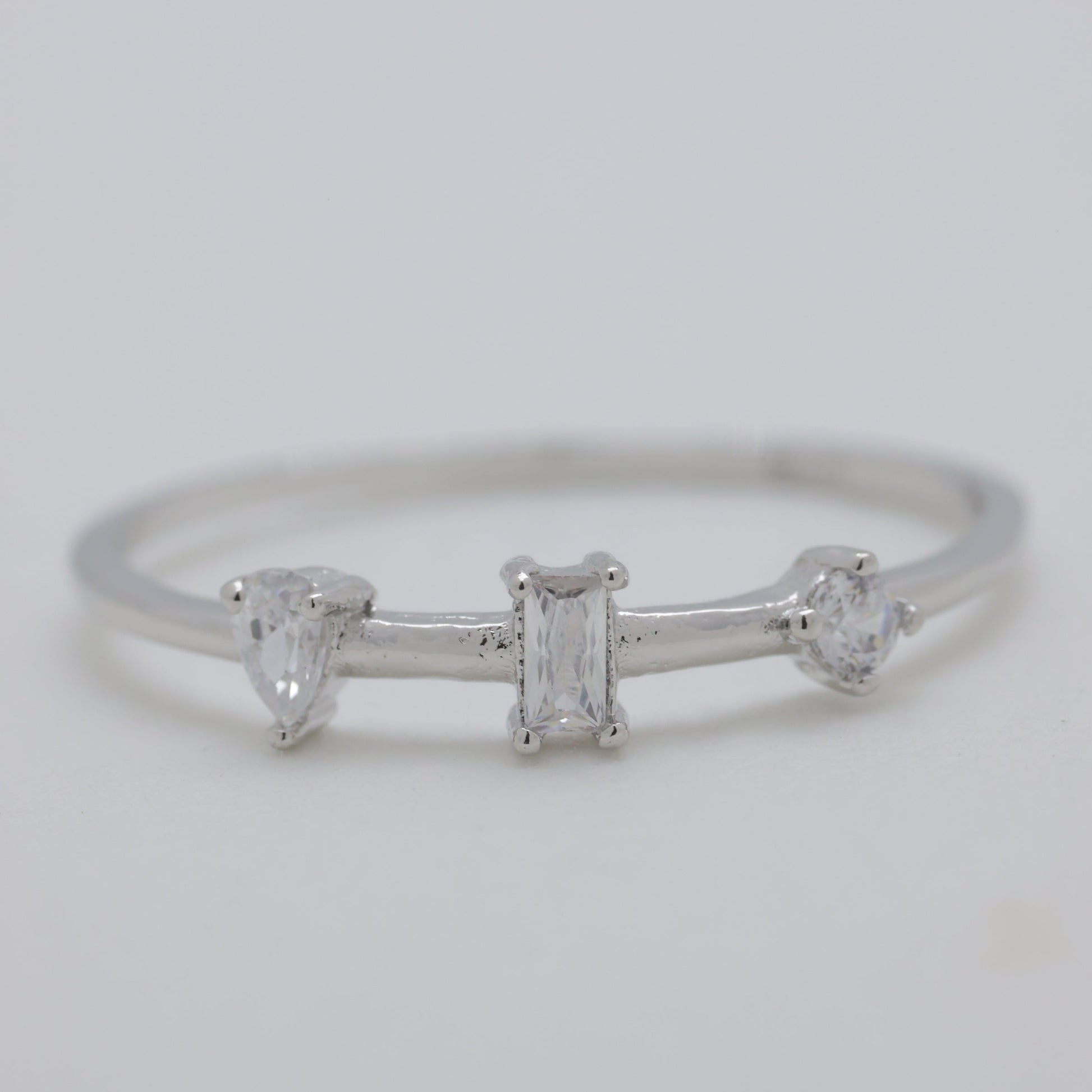 Silver ring with three diamonds on a light gray background