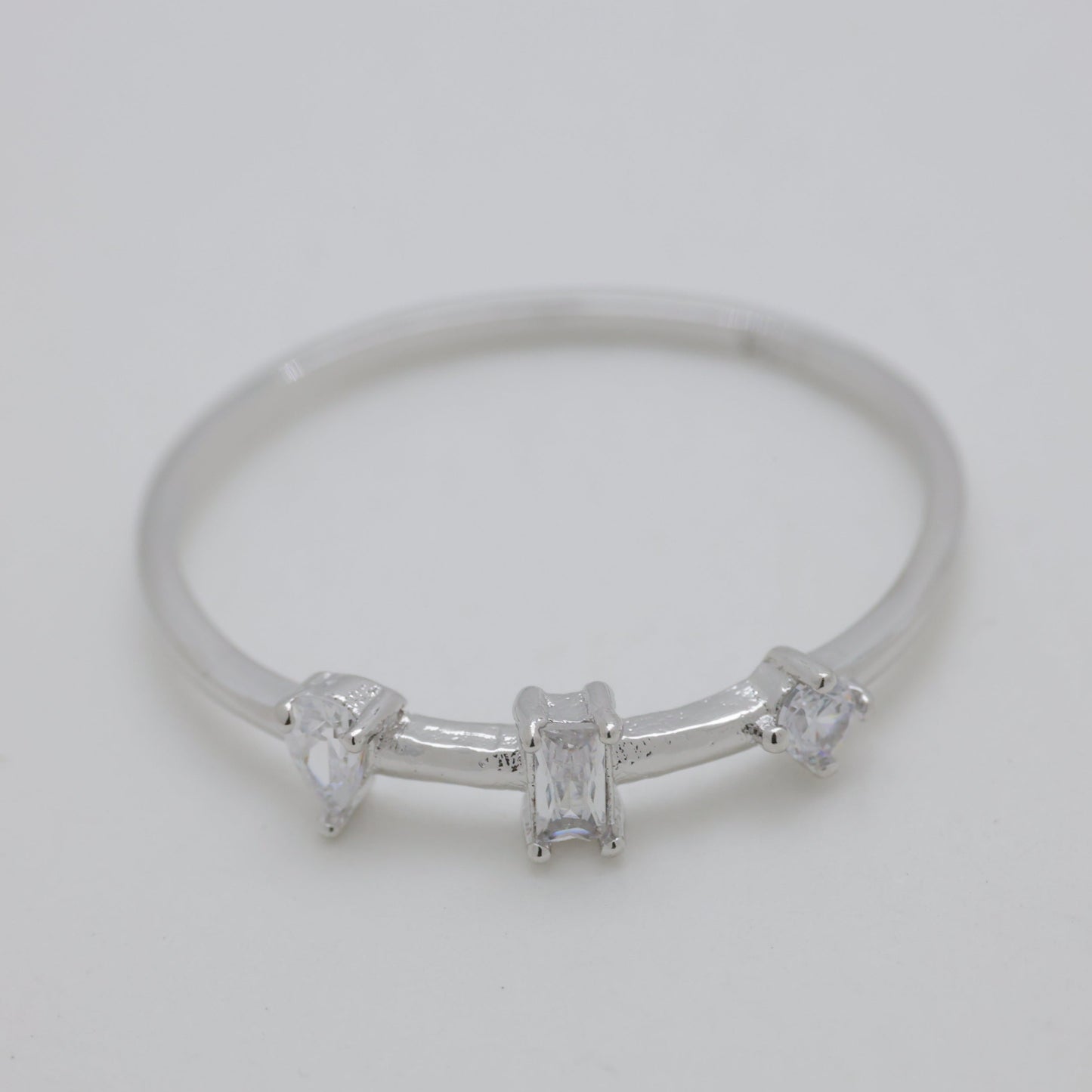 Silver ring with three small diamonds on a light gray background