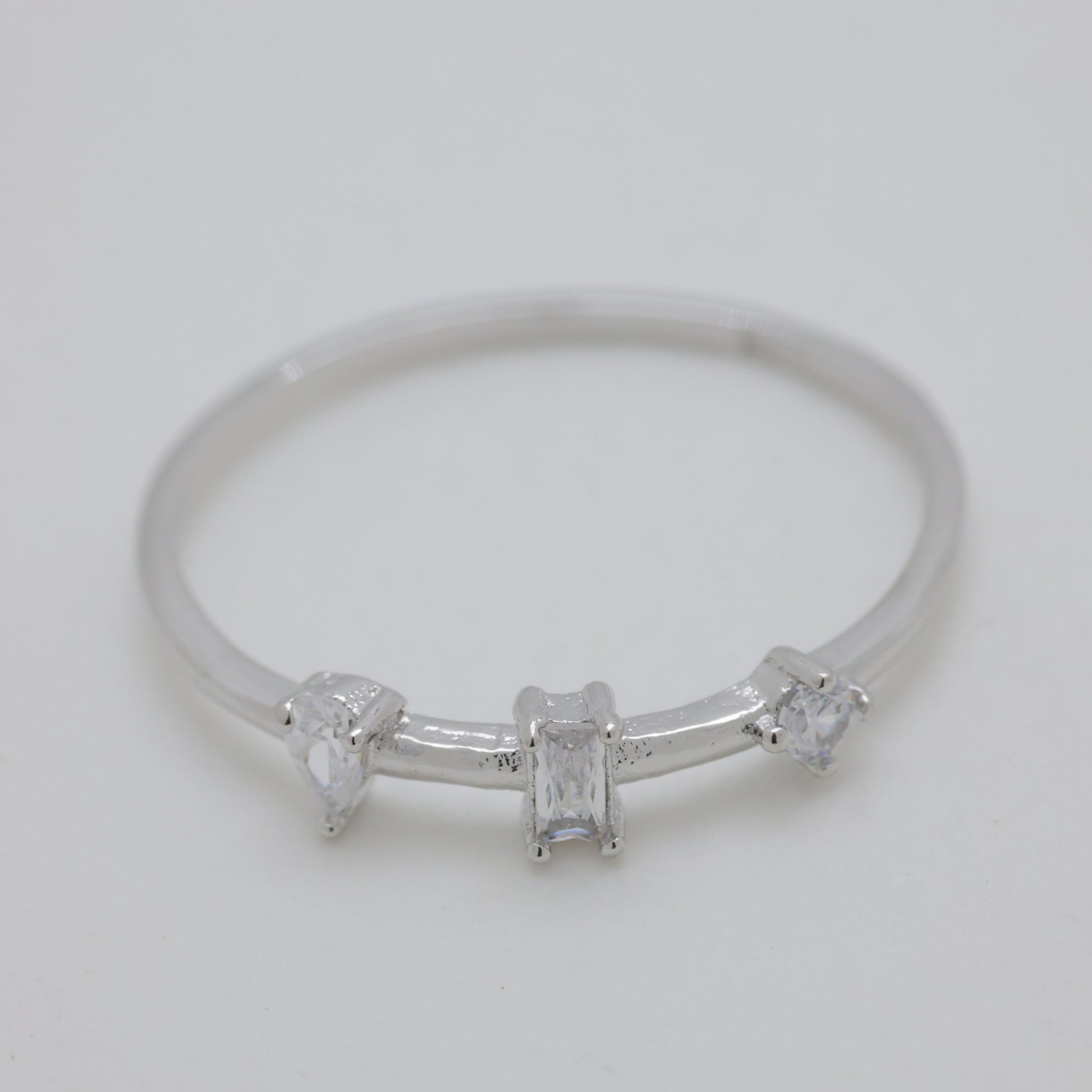 Silver ring with three small diamonds on a light gray background