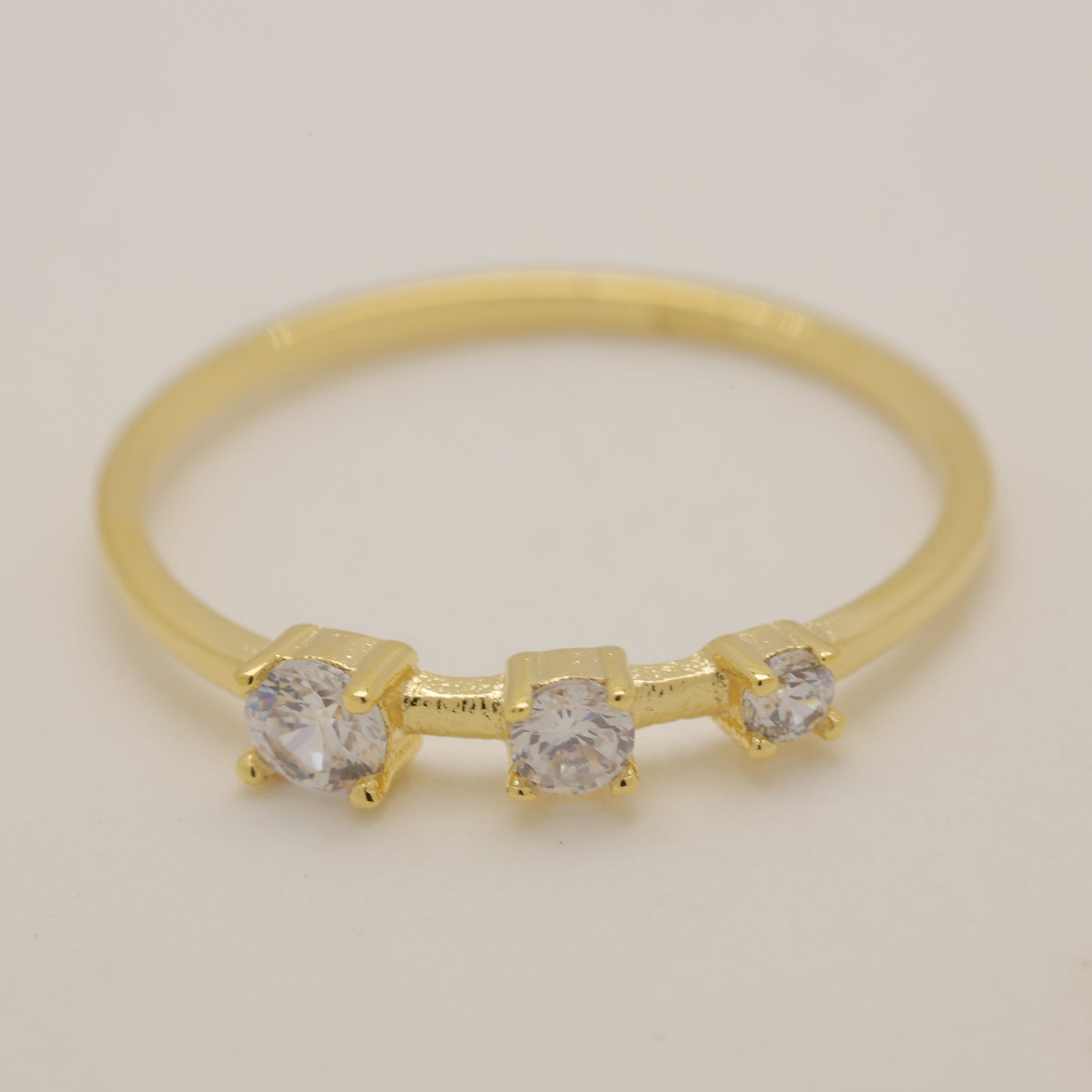 Gold ring with three diamonds on a light gray background