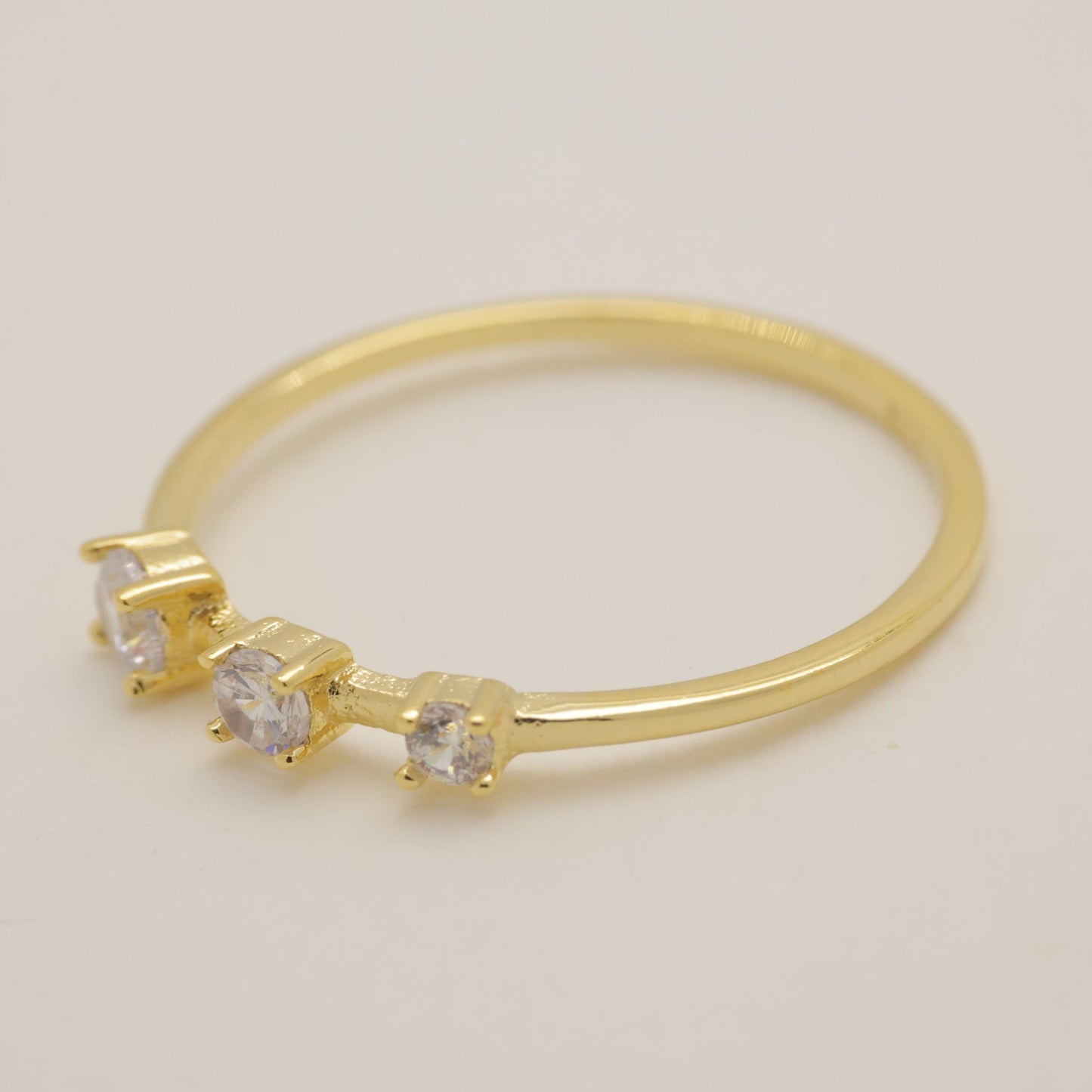 Gold ring with small diamonds on a light beige background