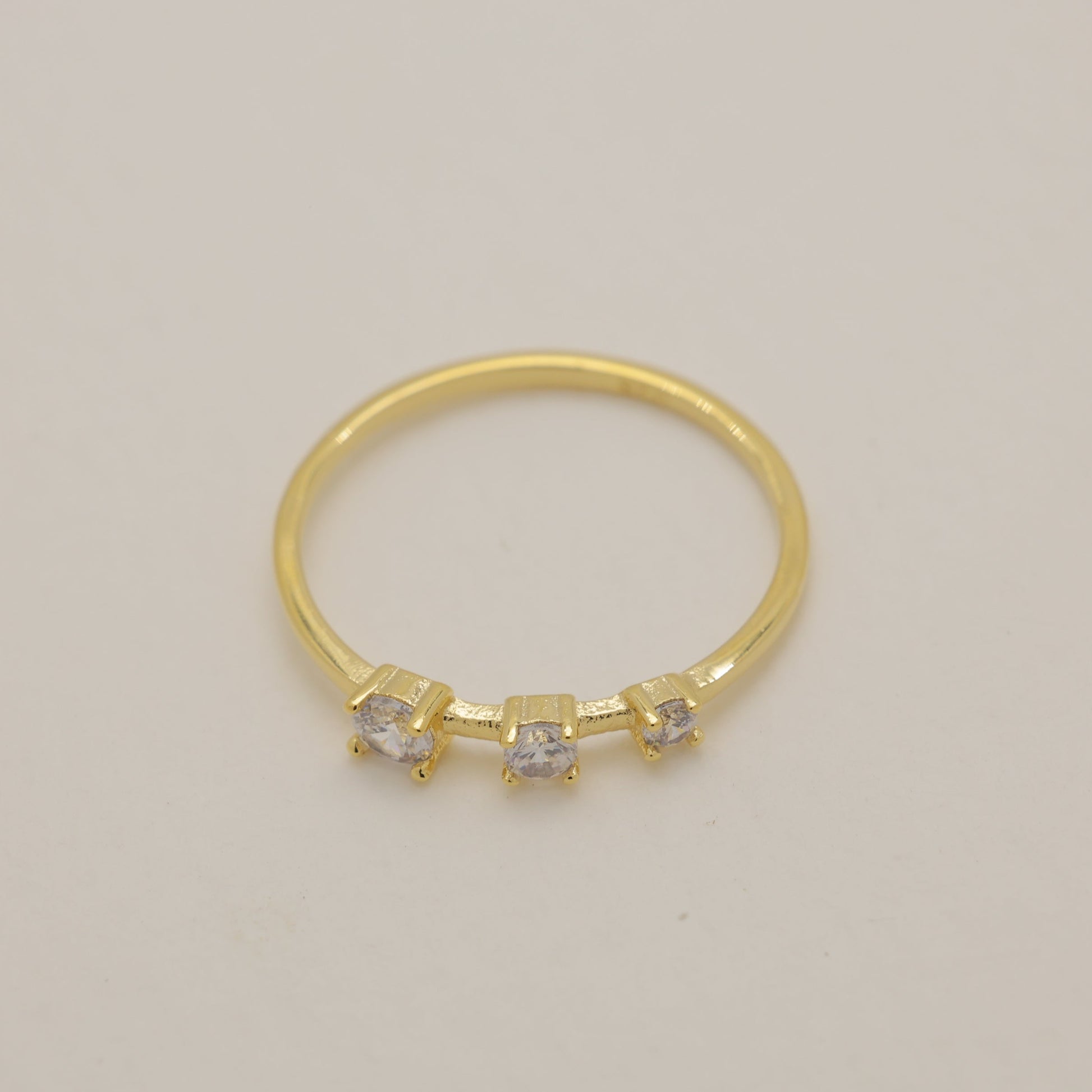 Gold ring with small diamonds on a beige background
