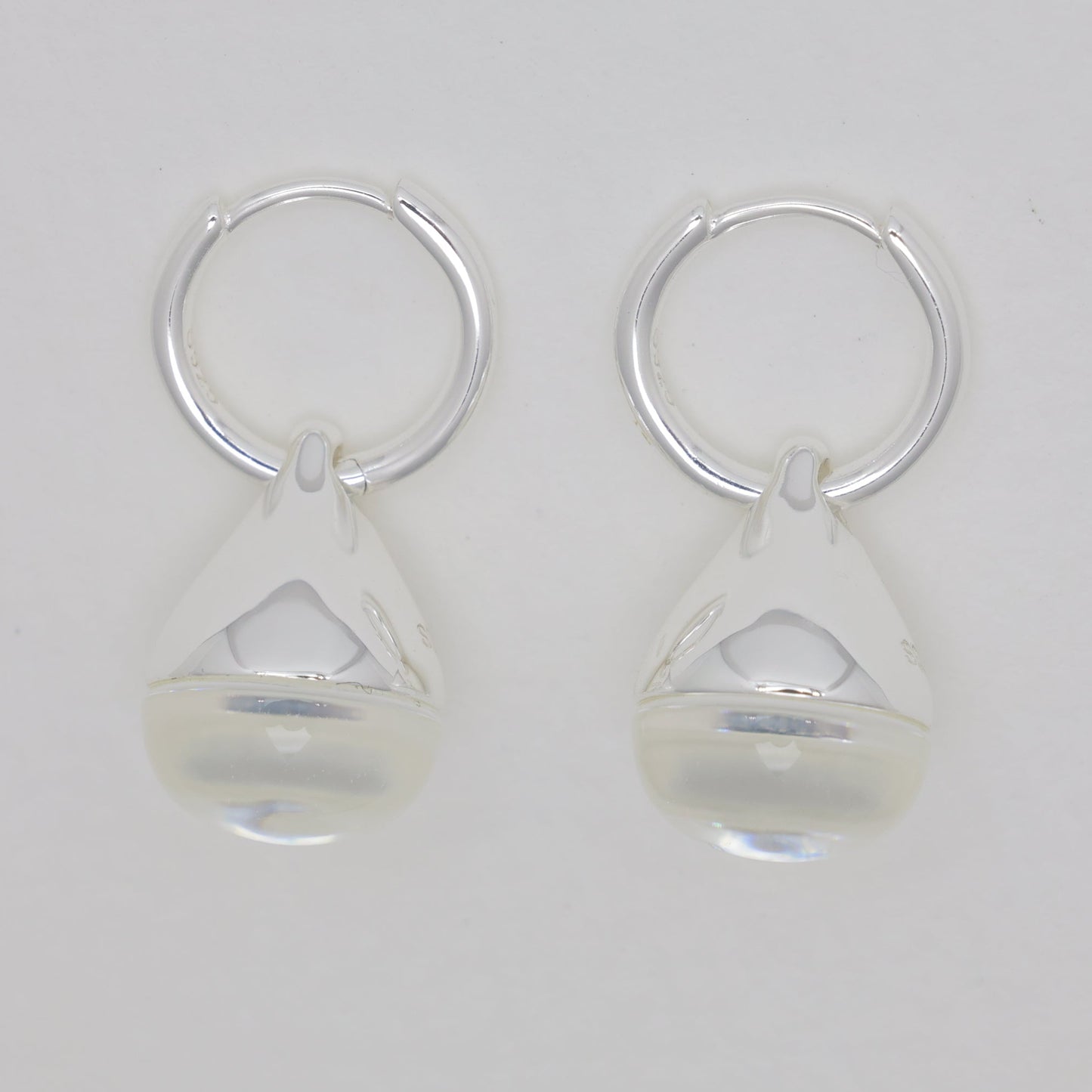 Pair of silver earrings with clear teardrop-shaped beads on a light gray background