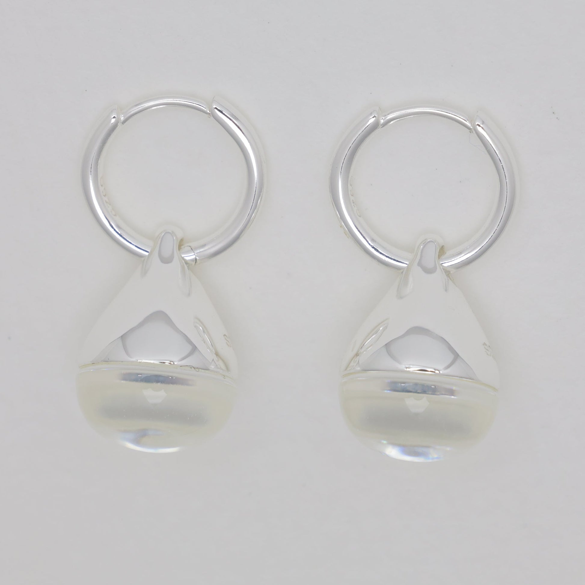Pair of silver earrings with clear teardrop-shaped beads on a light gray background