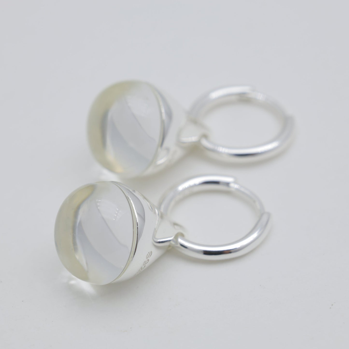 Three silver hoop earrings on a light gray background