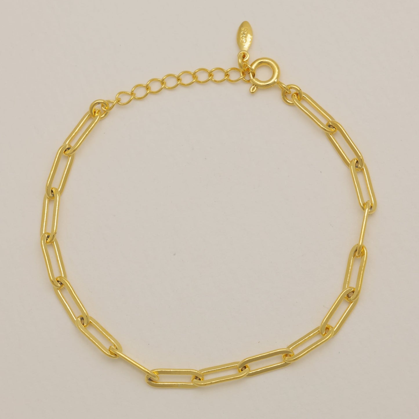 Gold chain bracelet on a beige background