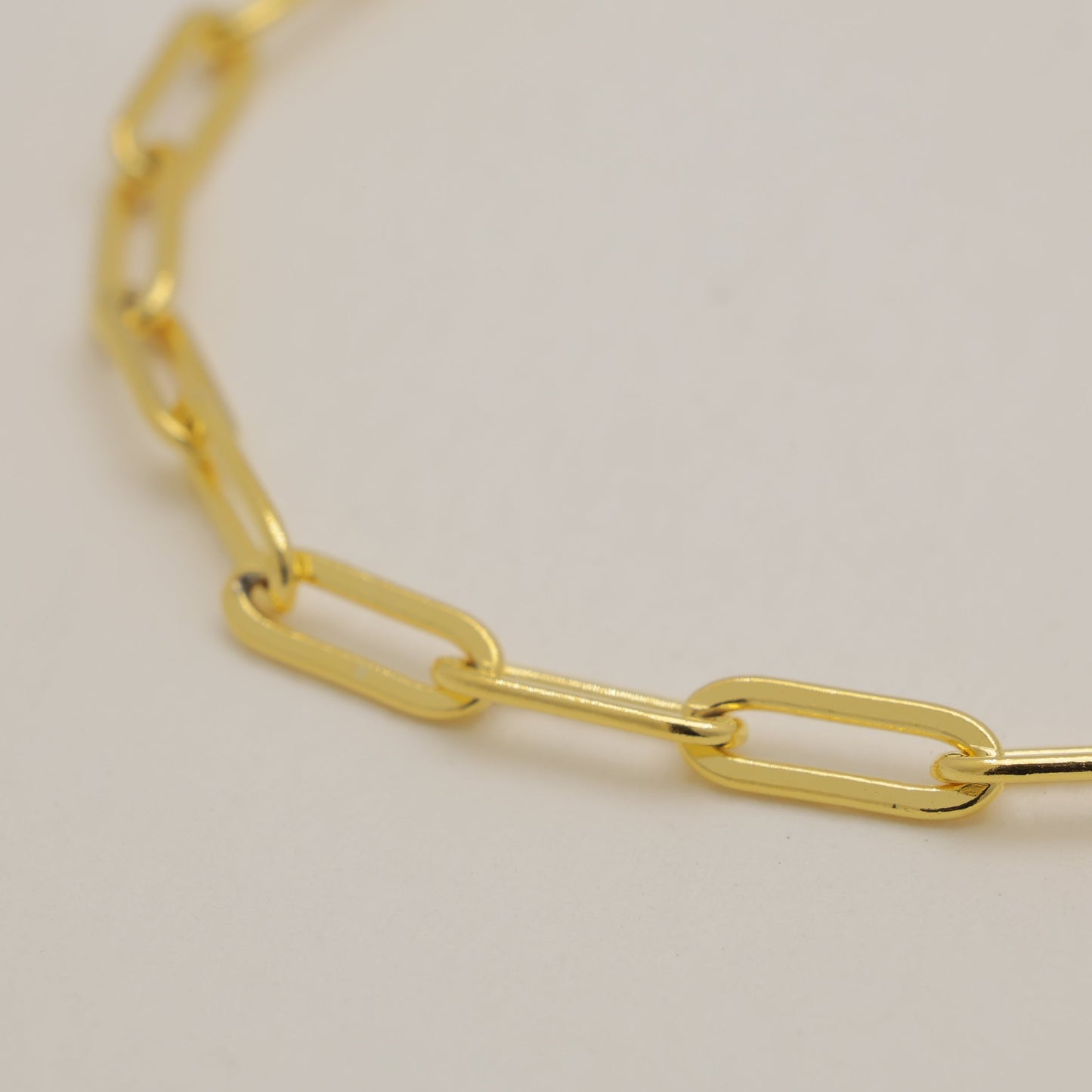 Gold chain bracelet on a light beige background