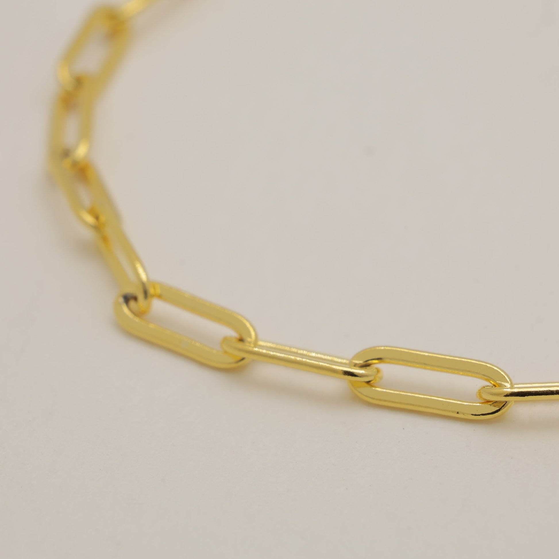 Gold chain bracelet on a light beige background