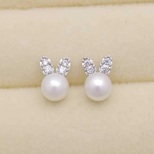 Pearl earrings with silver bunny ears on a beige background