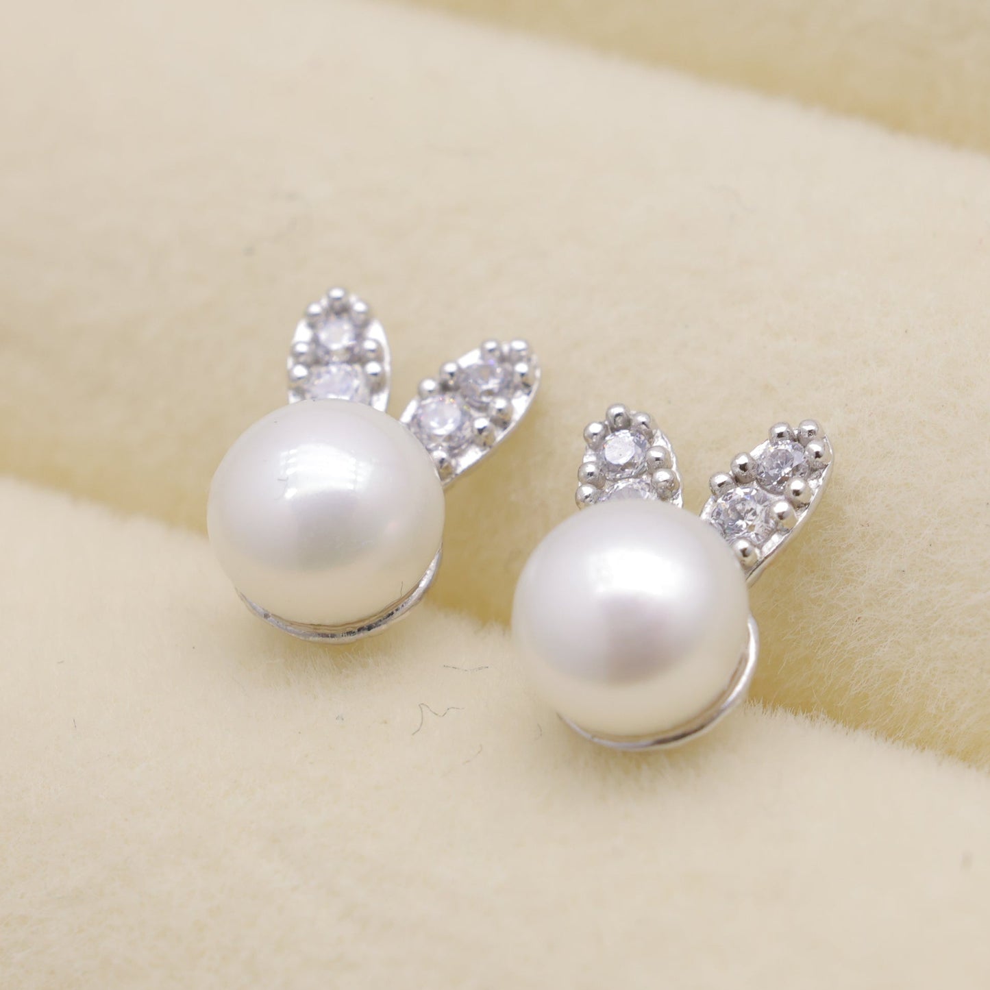 Pearl earrings with bunny ears on a beige background