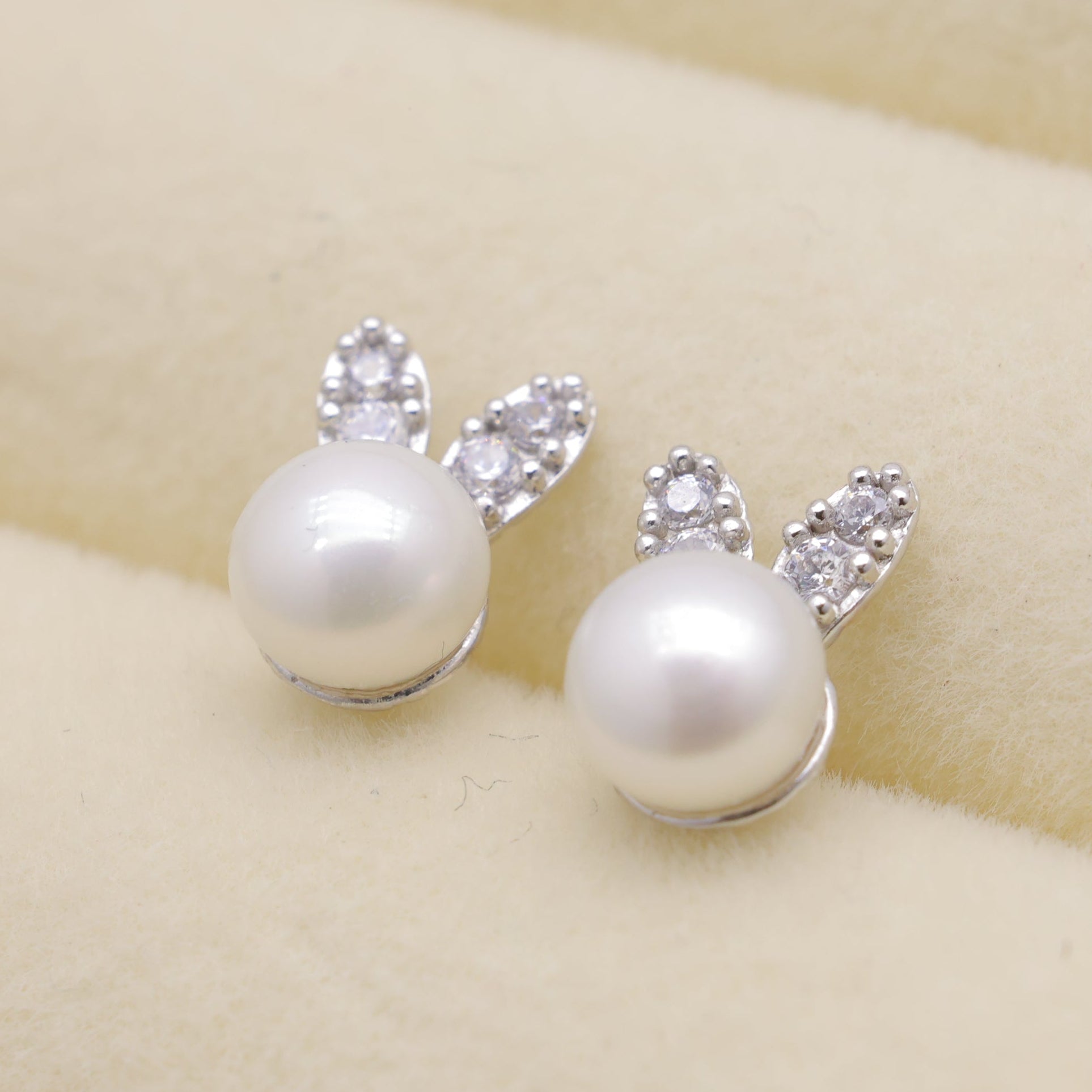 Pearl earrings with bunny ears on a beige background