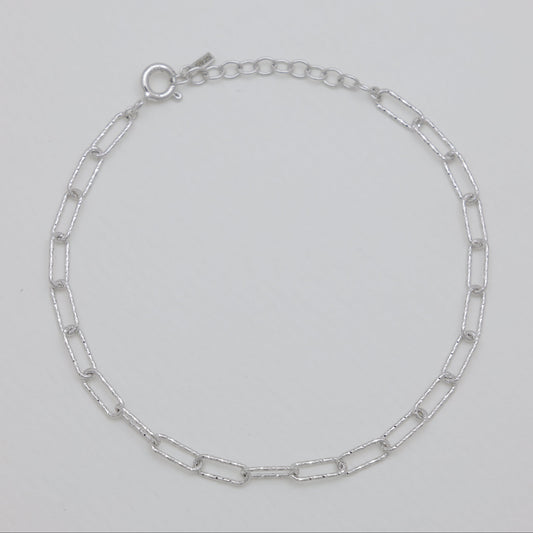 Silver chain bracelet on a light gray background