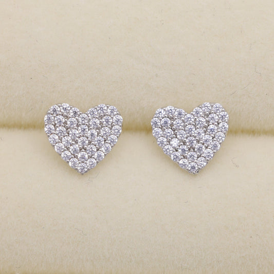 Heart-shaped diamond earrings on a beige cushion