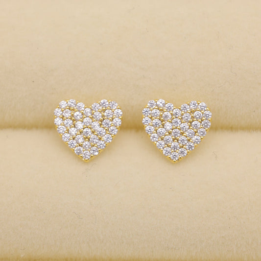 Heart-shaped earrings with diamond-like stones on a beige background