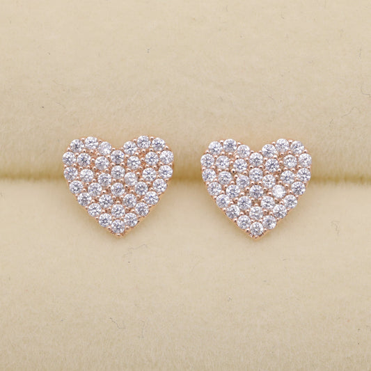 Heart-shaped diamond earrings on a beige background