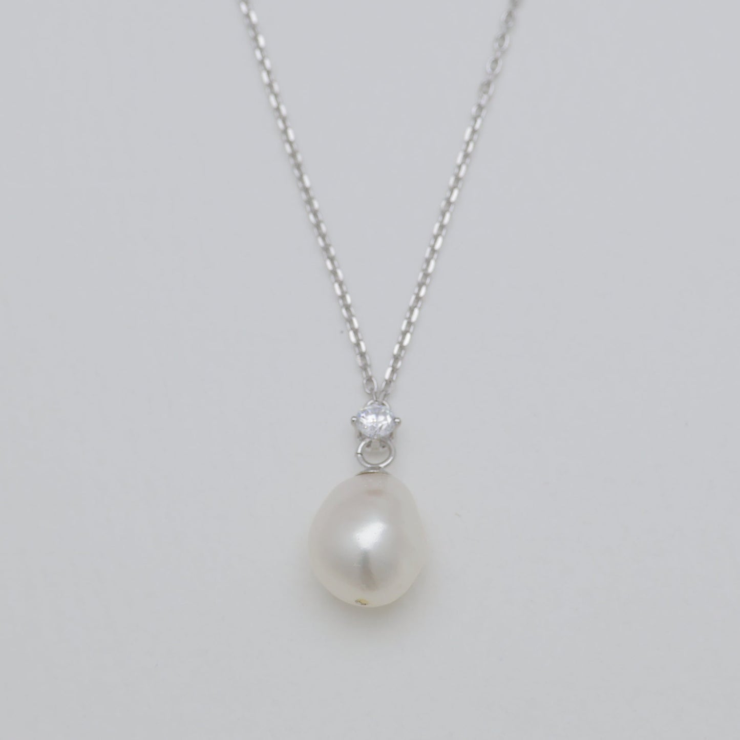 Pearl necklace with a silver chain on a light gray background