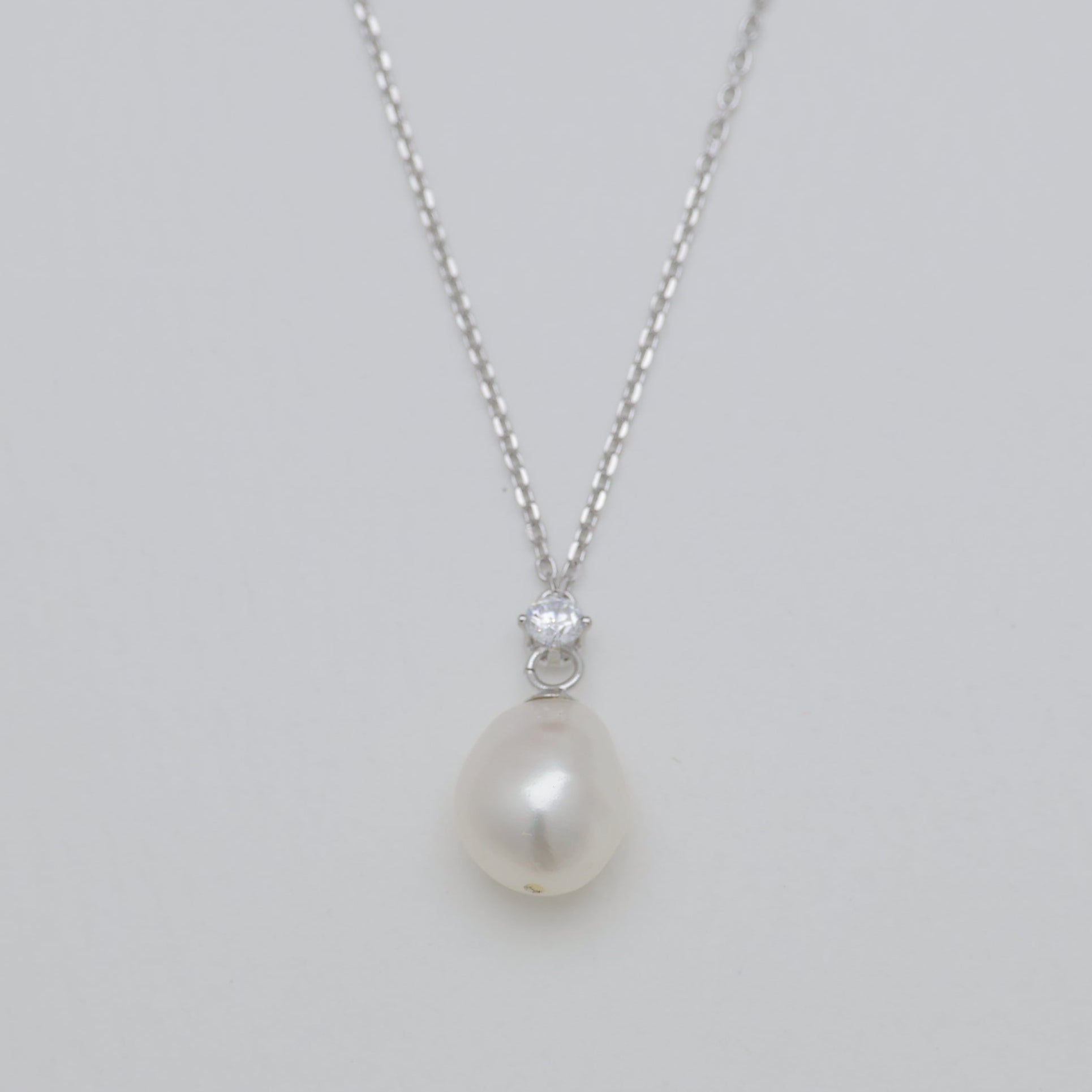Pearl necklace with a silver chain on a light gray background