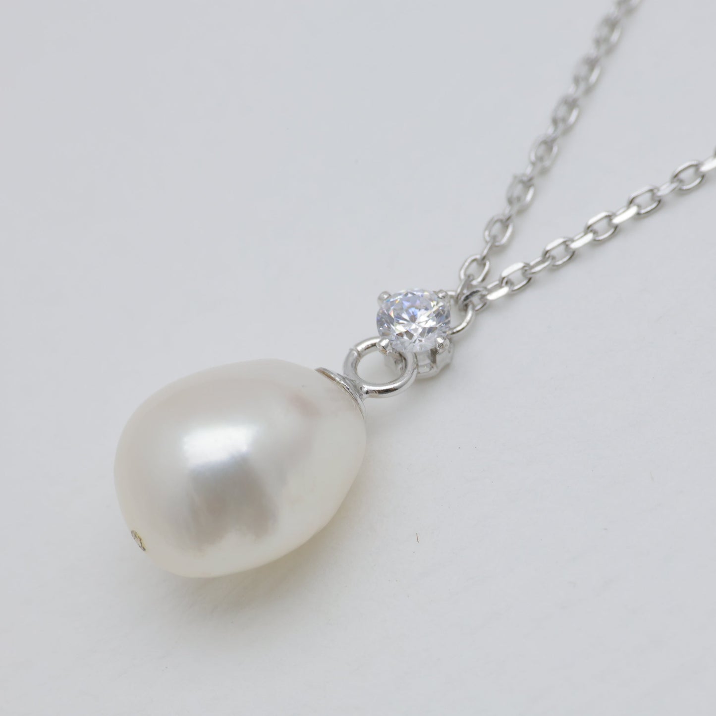 Pearl necklace with a silver chain on a light gray background