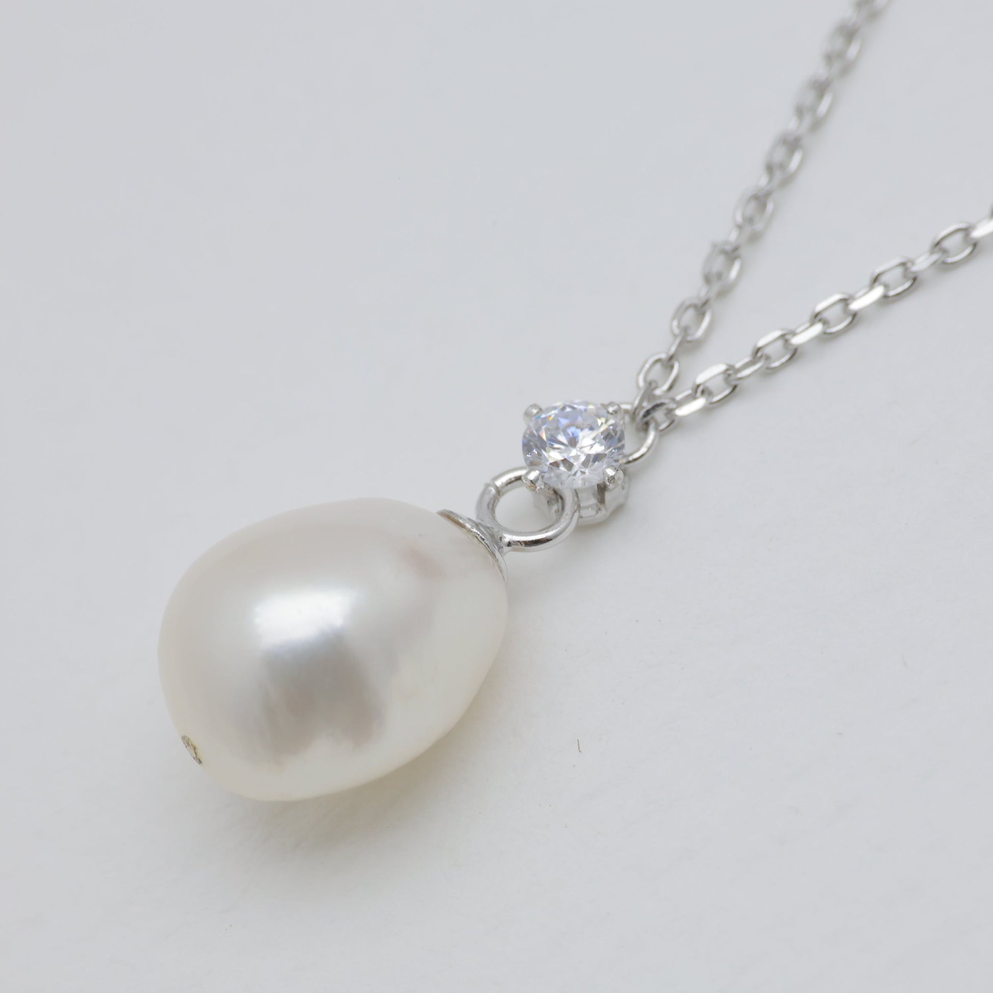 Pearl necklace with a silver chain on a light gray background