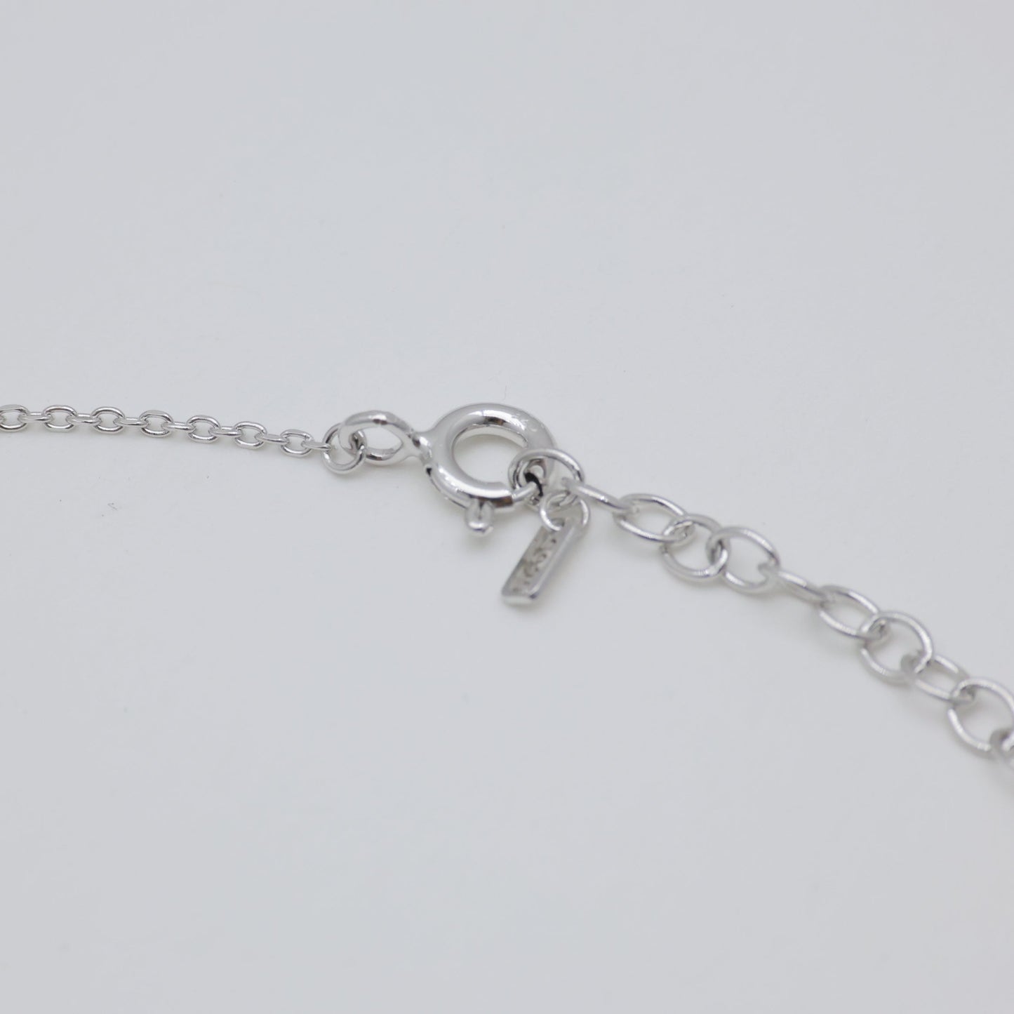 Close-up of a silver bracelet on a light gray background