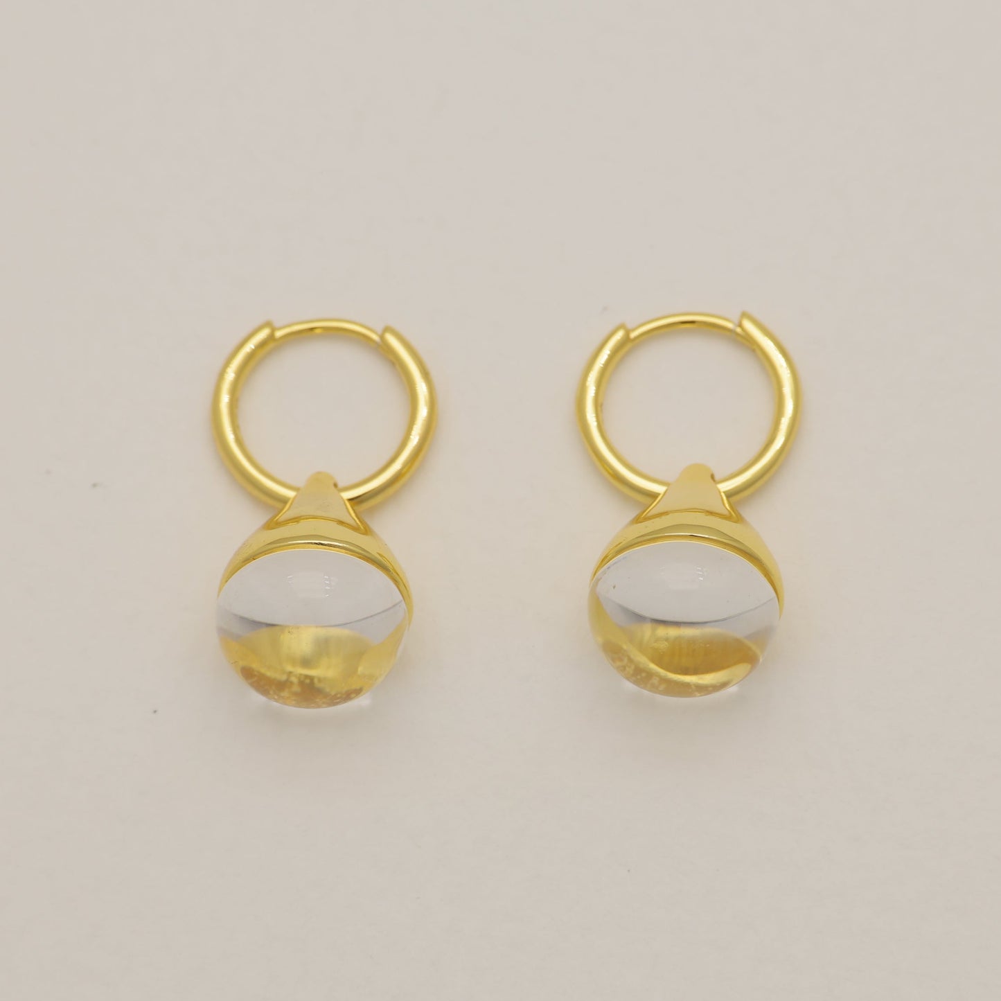 Pair of gold earrings with a beige background