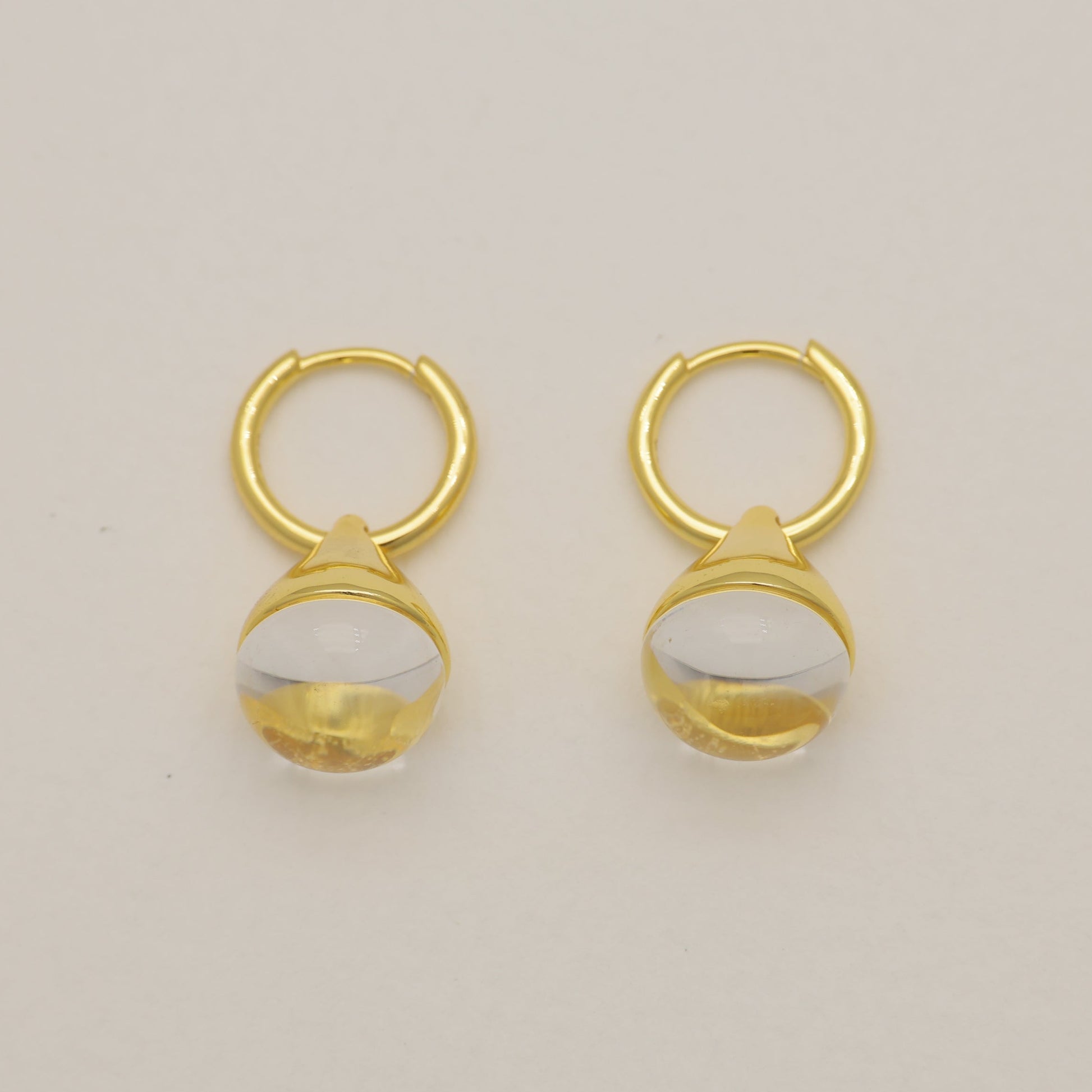 Pair of gold earrings with a beige background