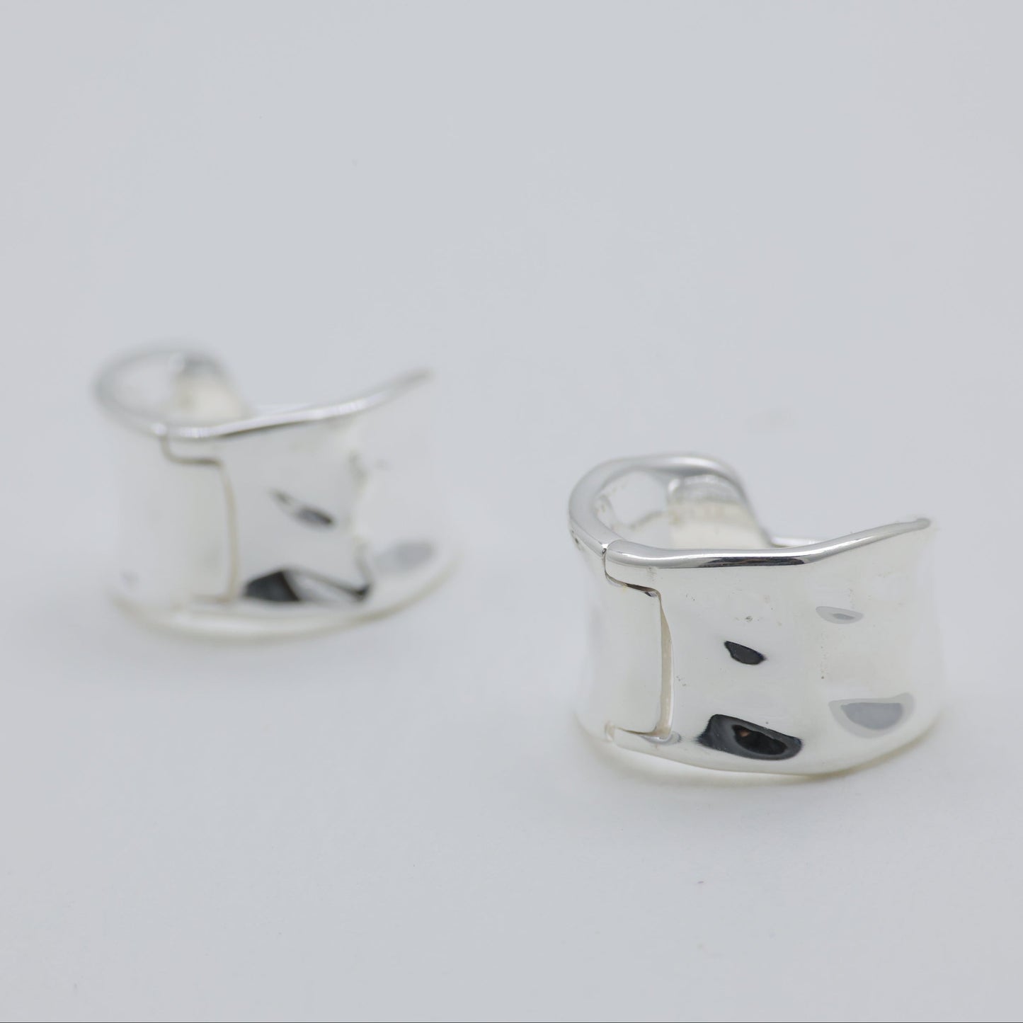 Silver cat-shaped earrings on a light gray background