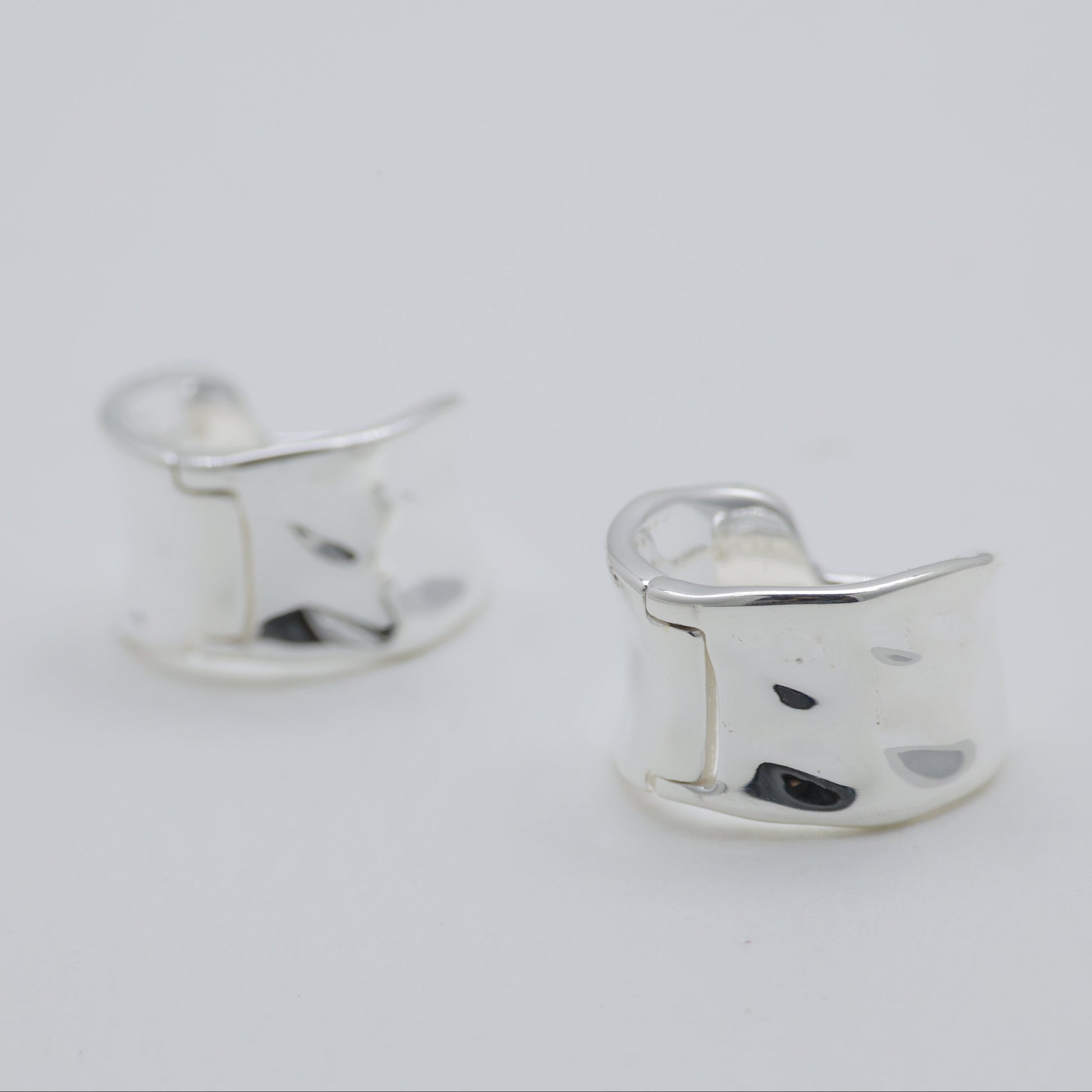 Silver cat-shaped earrings on a light gray background