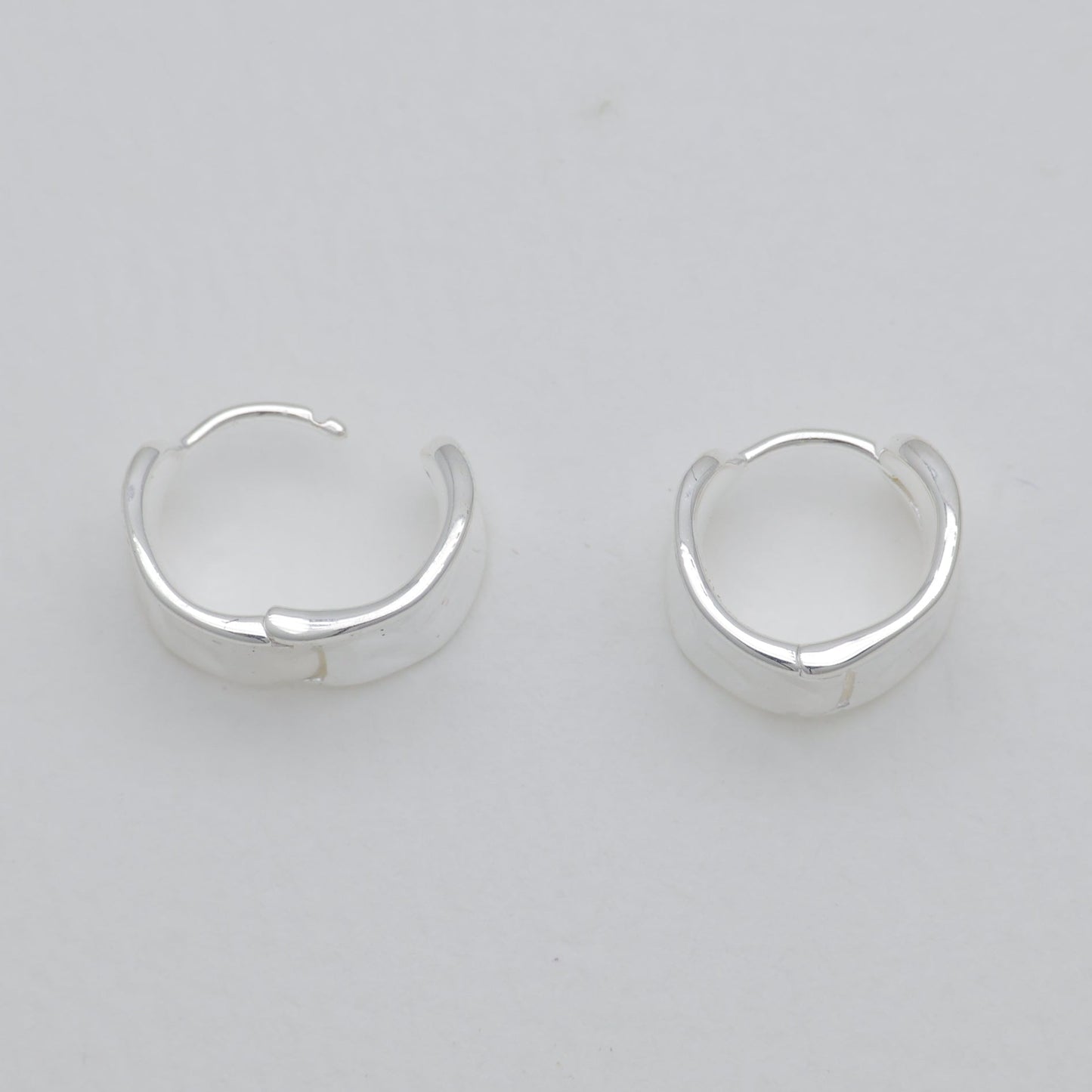 Pair of silver hoop earrings on a light gray background