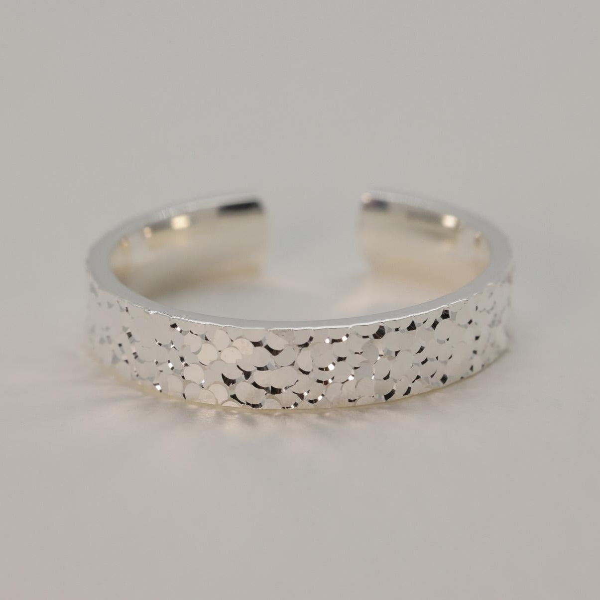 Silver ring with textured surface on a light gray background