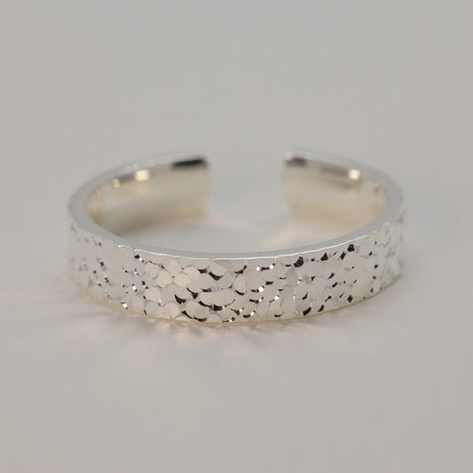 Silver ring with textured surface on a light gray background