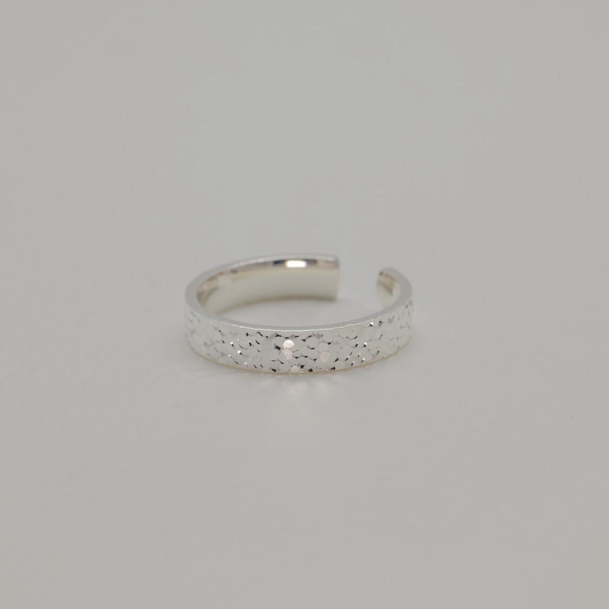 Silver ring with textured band on a light gray background