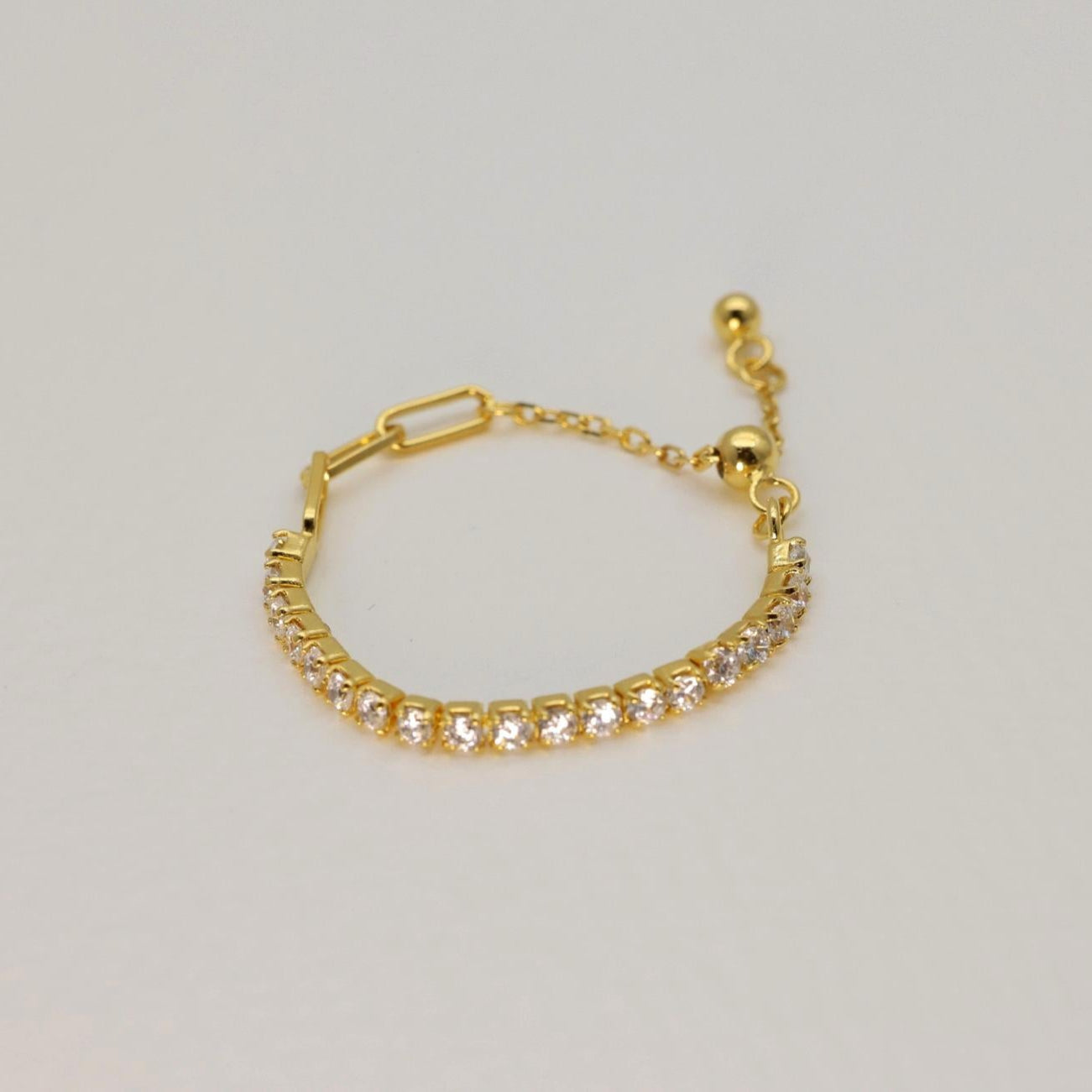 Gold vermeil adjustable pavé ring featuring a row of cubic zirconia stones, open back for easy sizing, styled on a neutral background.