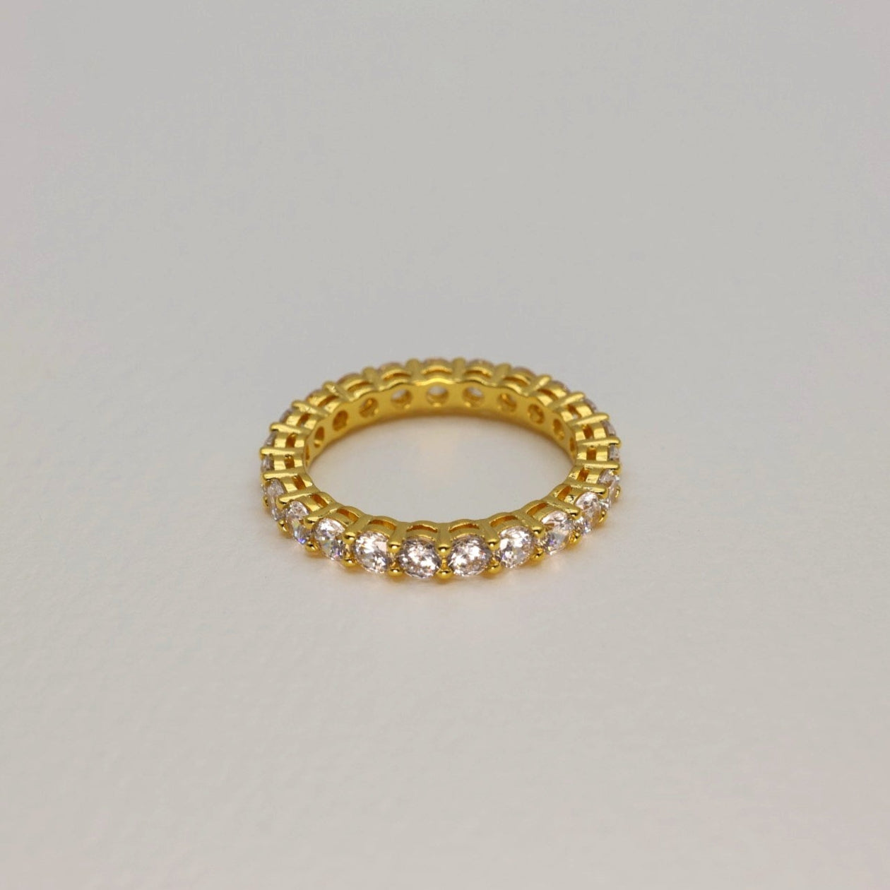 Gold ring with small diamonds on a light gray background