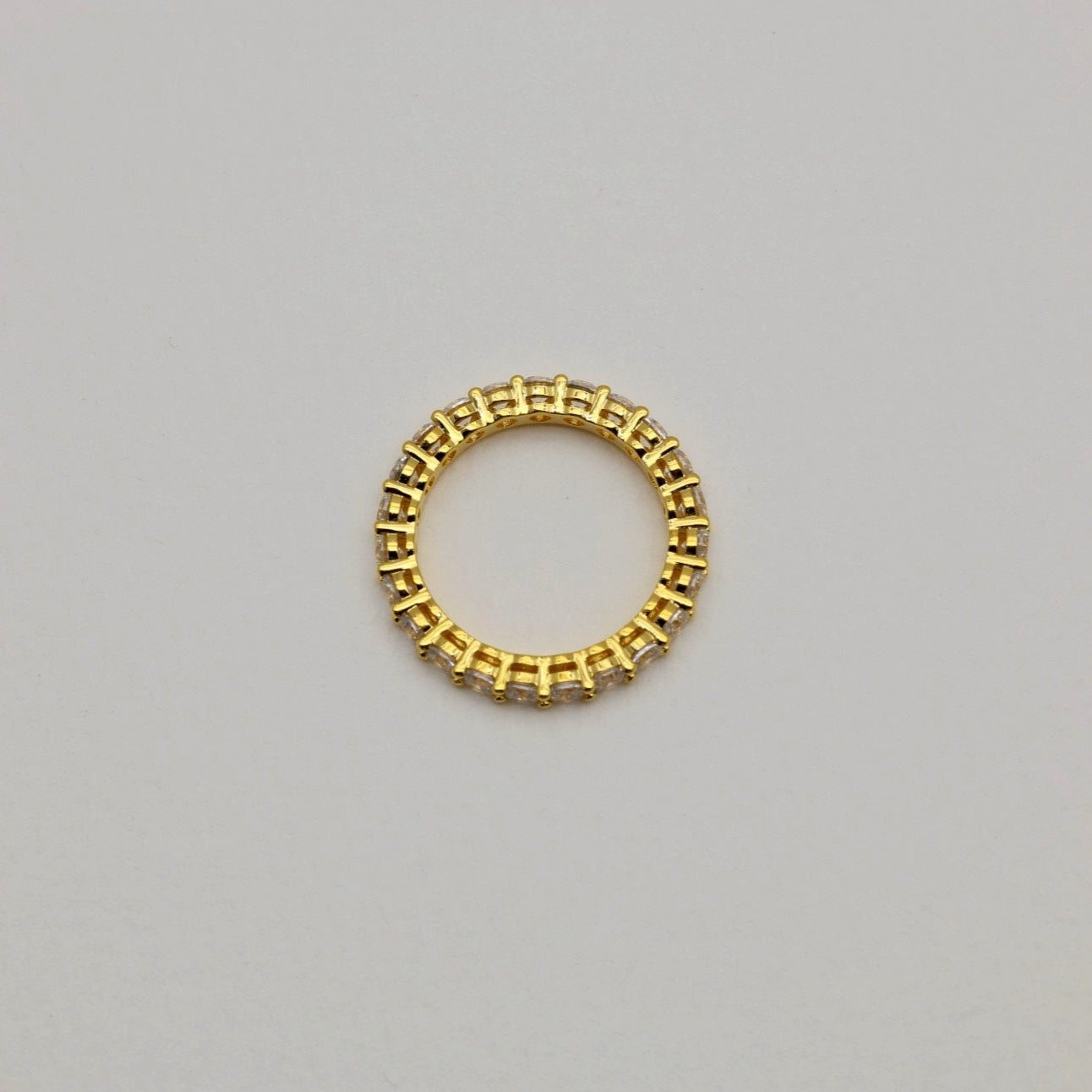 Gold ring with a beaded design on a light gray background