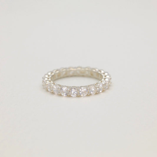Silver ring with small diamonds on a light gray background