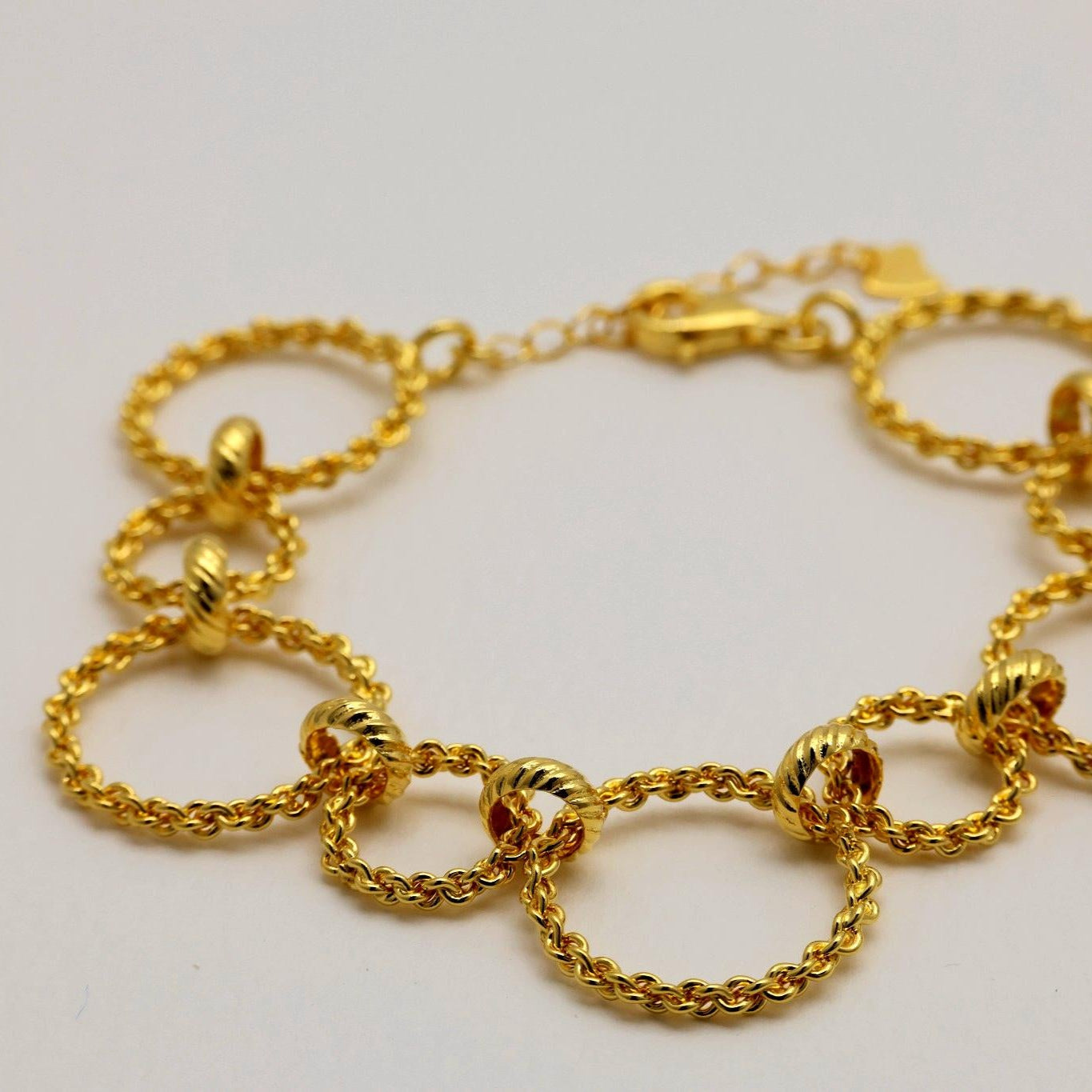 Close-up view of Ariette bracelet highlighting twisted gold rope circles and polished links.
